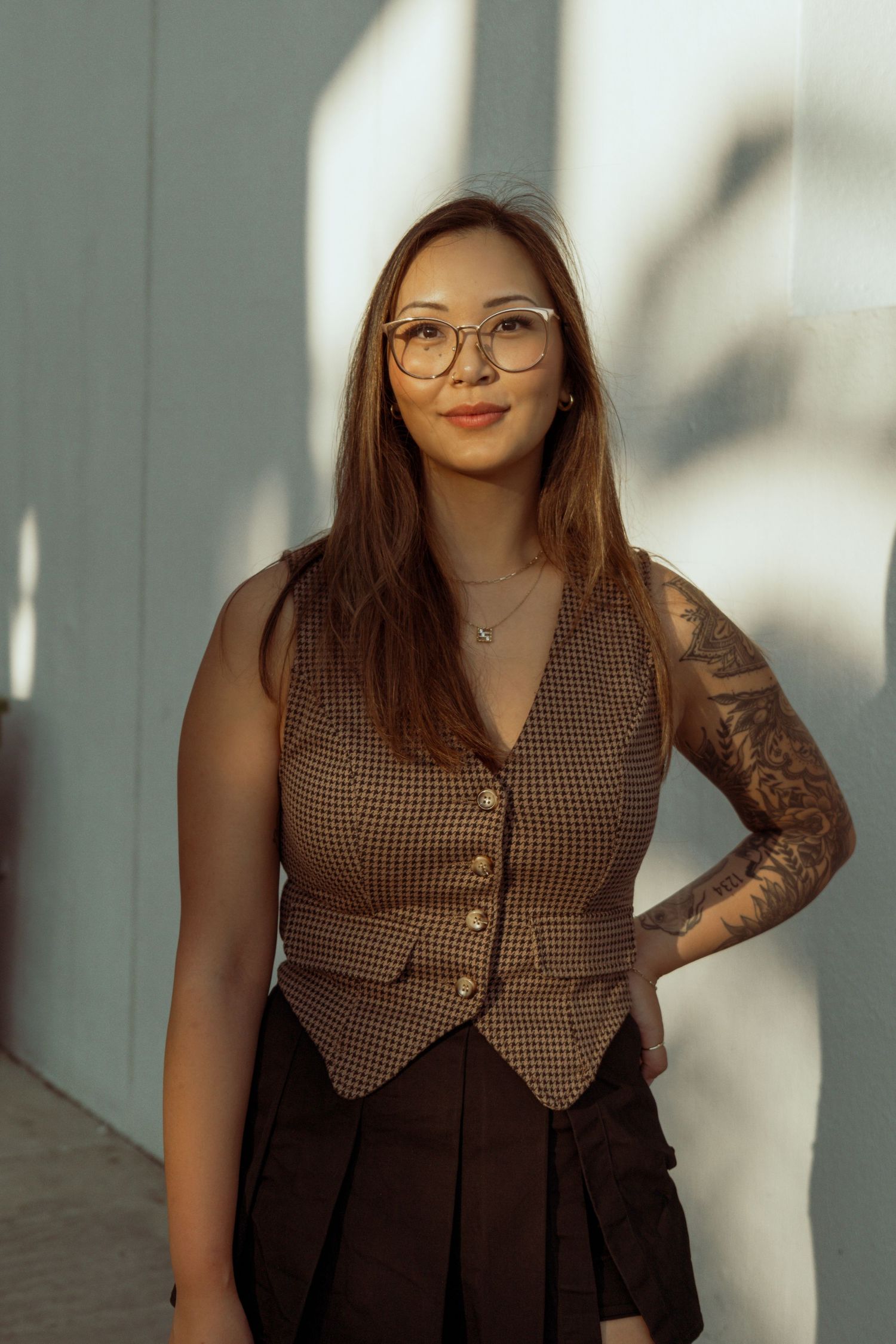 Series of fashion portraits showing a person in a brown checkered vest and glasses posing against a light wall.Photo shot by Mikiah Nicole D
