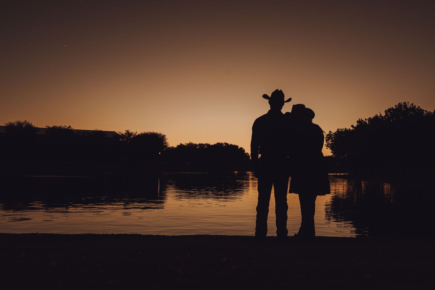 Romantic Des Moines wedding silhouette couple embracing at golden hour by Iowa lake, documentary style
