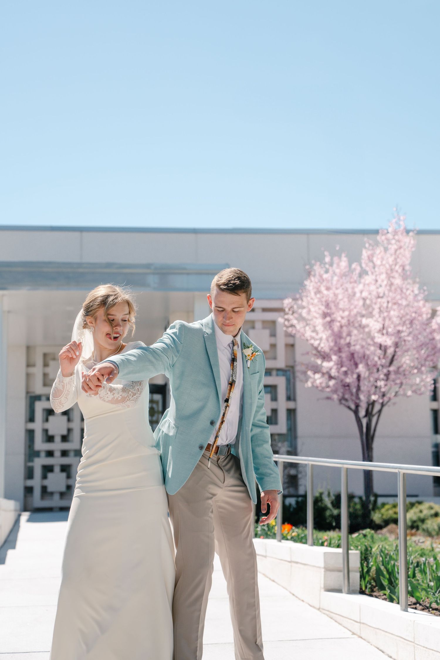 Bride and groom celebrating outside a temple during a bright spring wedding portrait session.