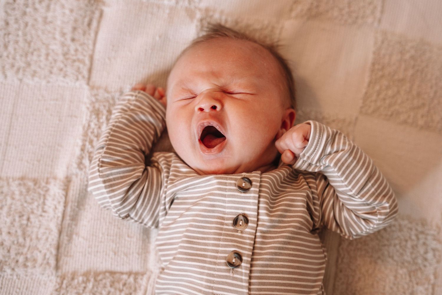 Newborn baby yawning during a cozy lifestyle newborn Des Moines photography session.