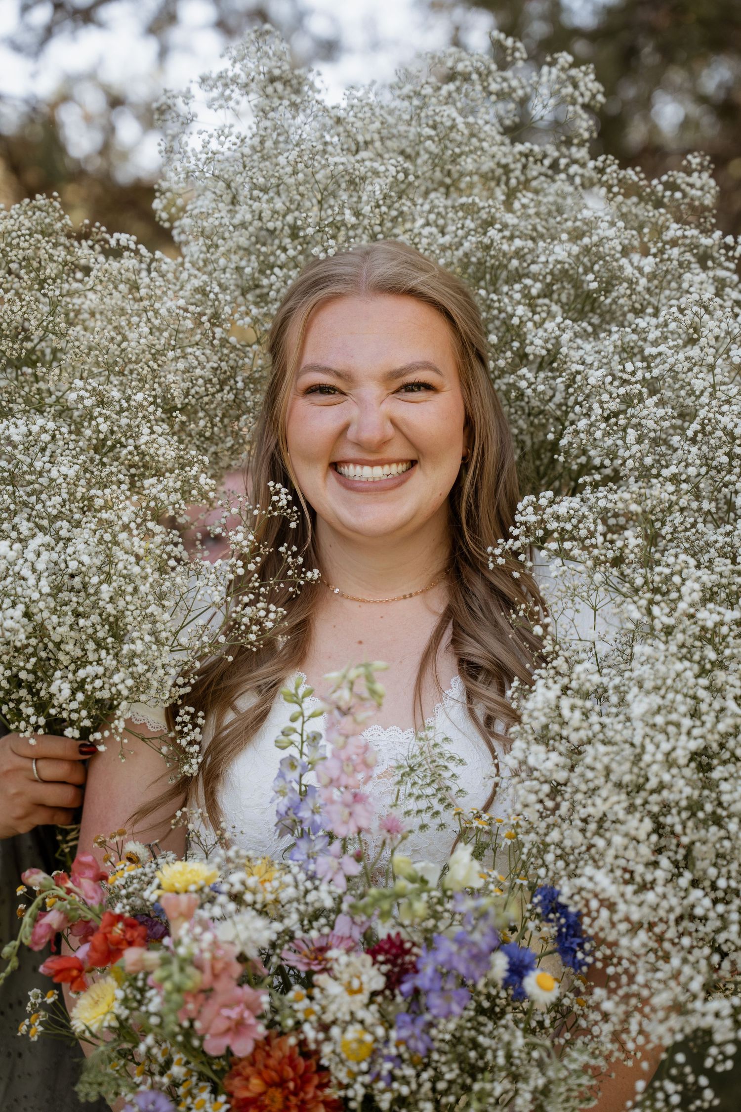 Iowa bride surrounded by bridesmaids bouquets on a warm sunny day. Wildflower and baby's breath bouquet.