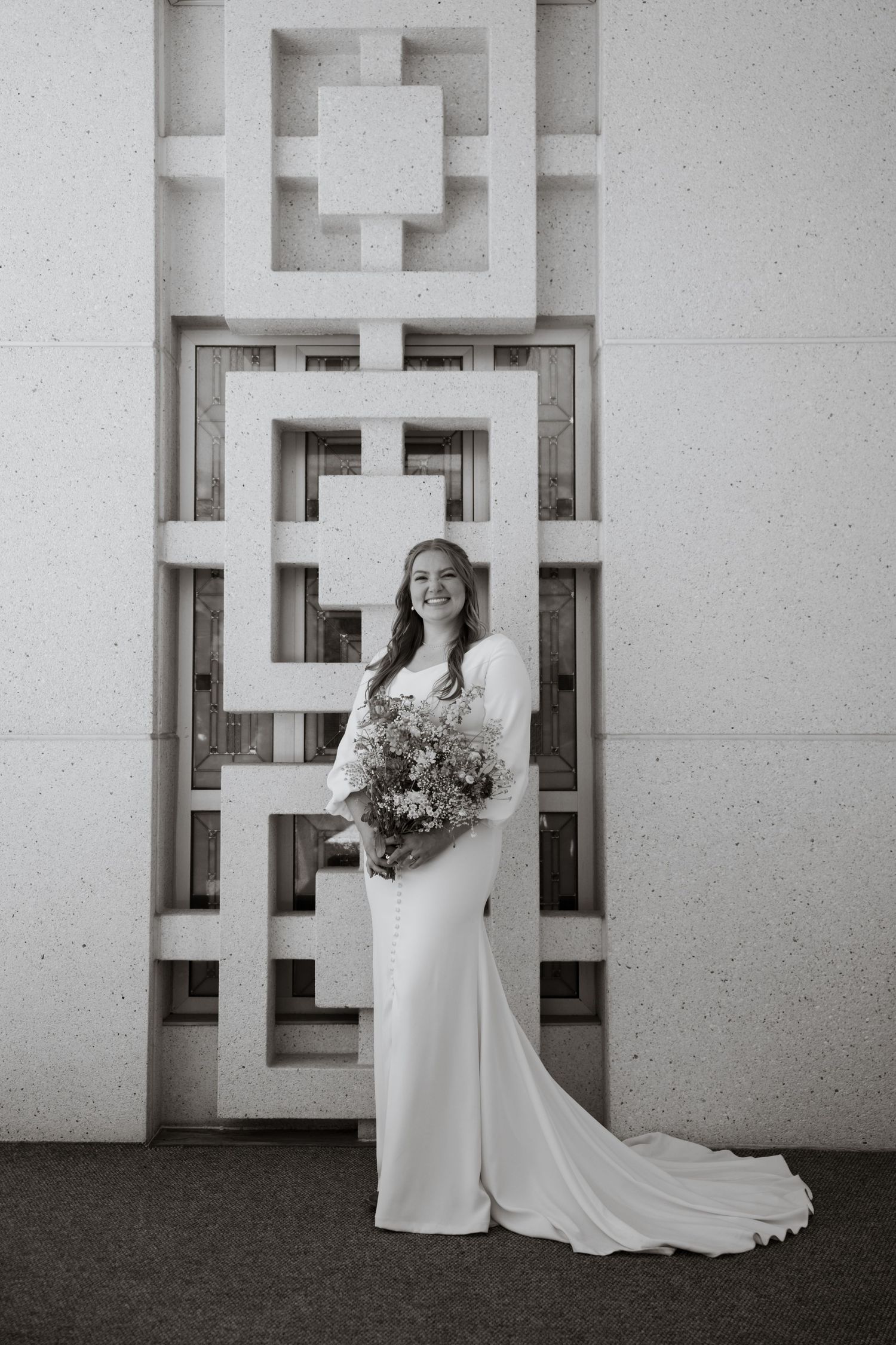 Des Moines Iowa wedding photographer – elegant bride in white gown posing in front of modern geometric temple architecture.