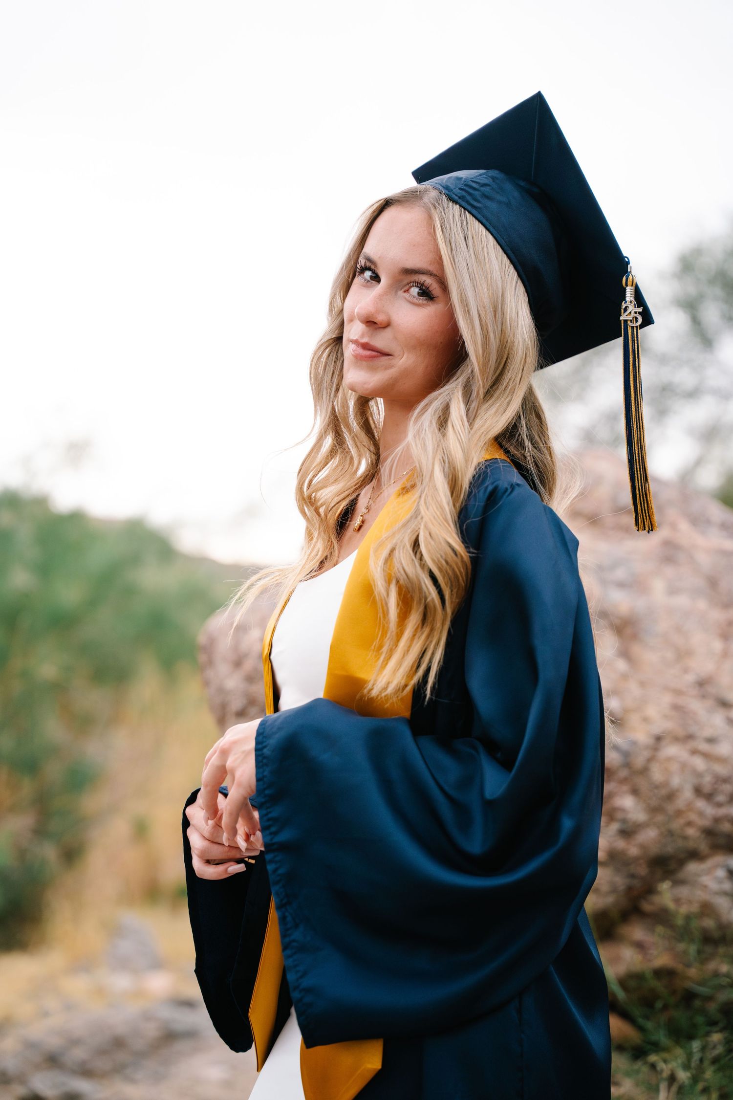 Des Moines Iowa senior portrait photographer – happy teenage girl in graduation gown with a warm smile and throwing her cap up in the air.