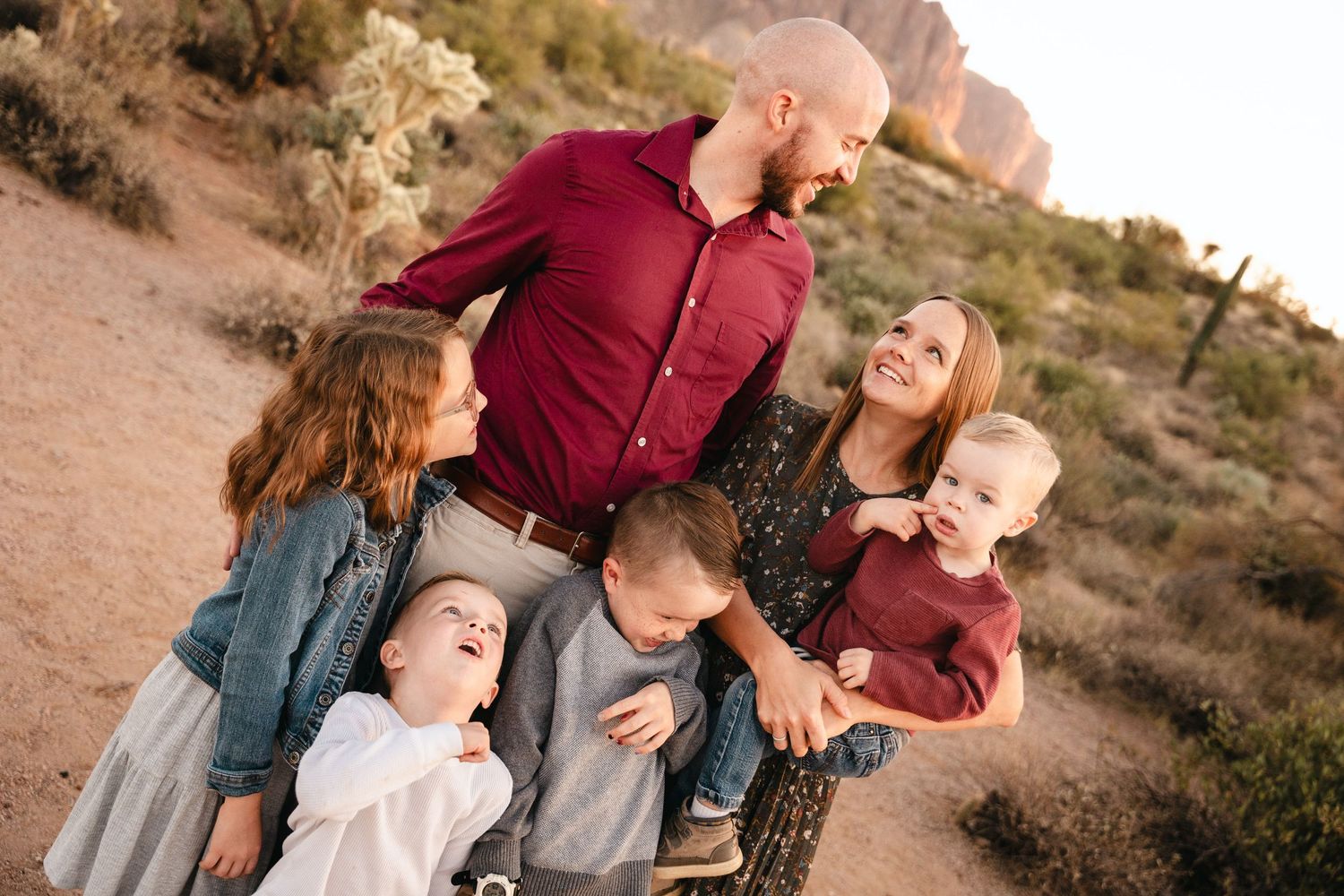Des Moines Iowa family photography – candid desert portrait of parents and three kids smiling together at golden hour, authentic family hugs