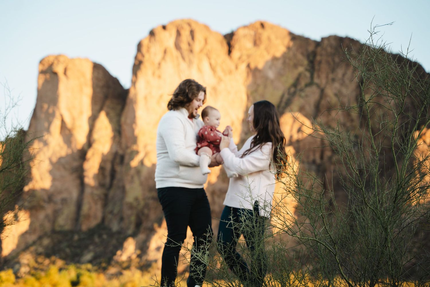 Des Moines Iowa family photography – young parents and toddler in desert landscape, mom cradling baby, warm golden-hour family moment.