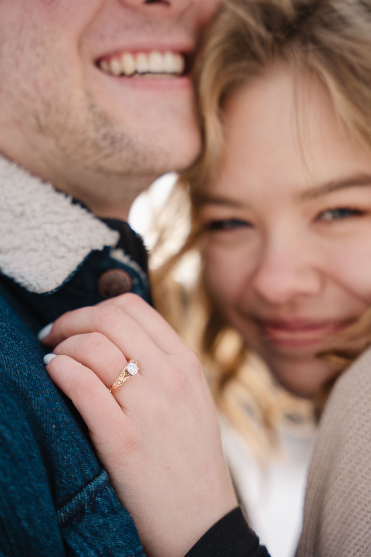 Des Moines winter engagement photography – groom kissing bride's forehead, close-up with sparkling engagement ring in soft light
