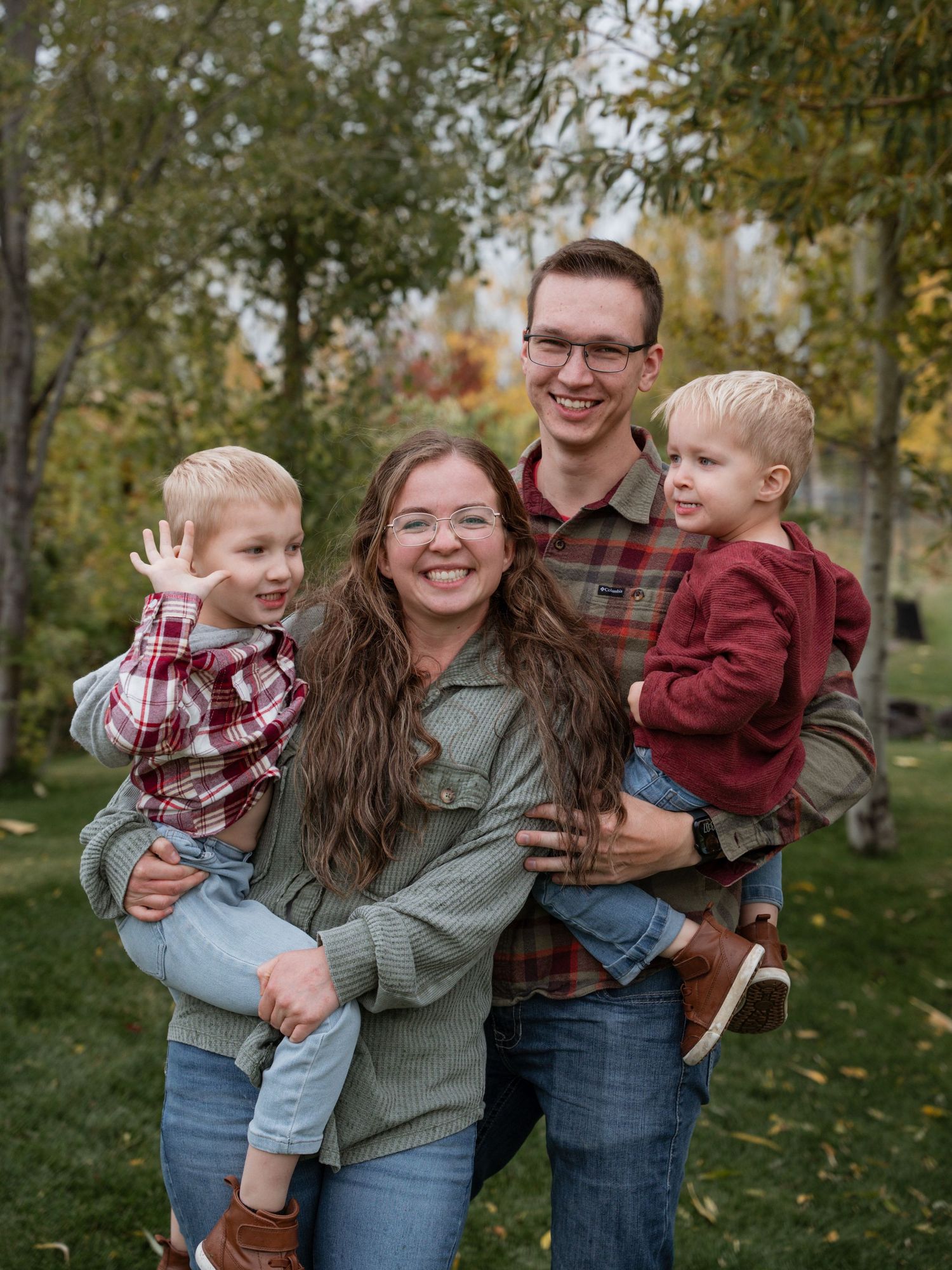 Young family portrait in the fall with leaves changing colors in Des Moines, Iowa.