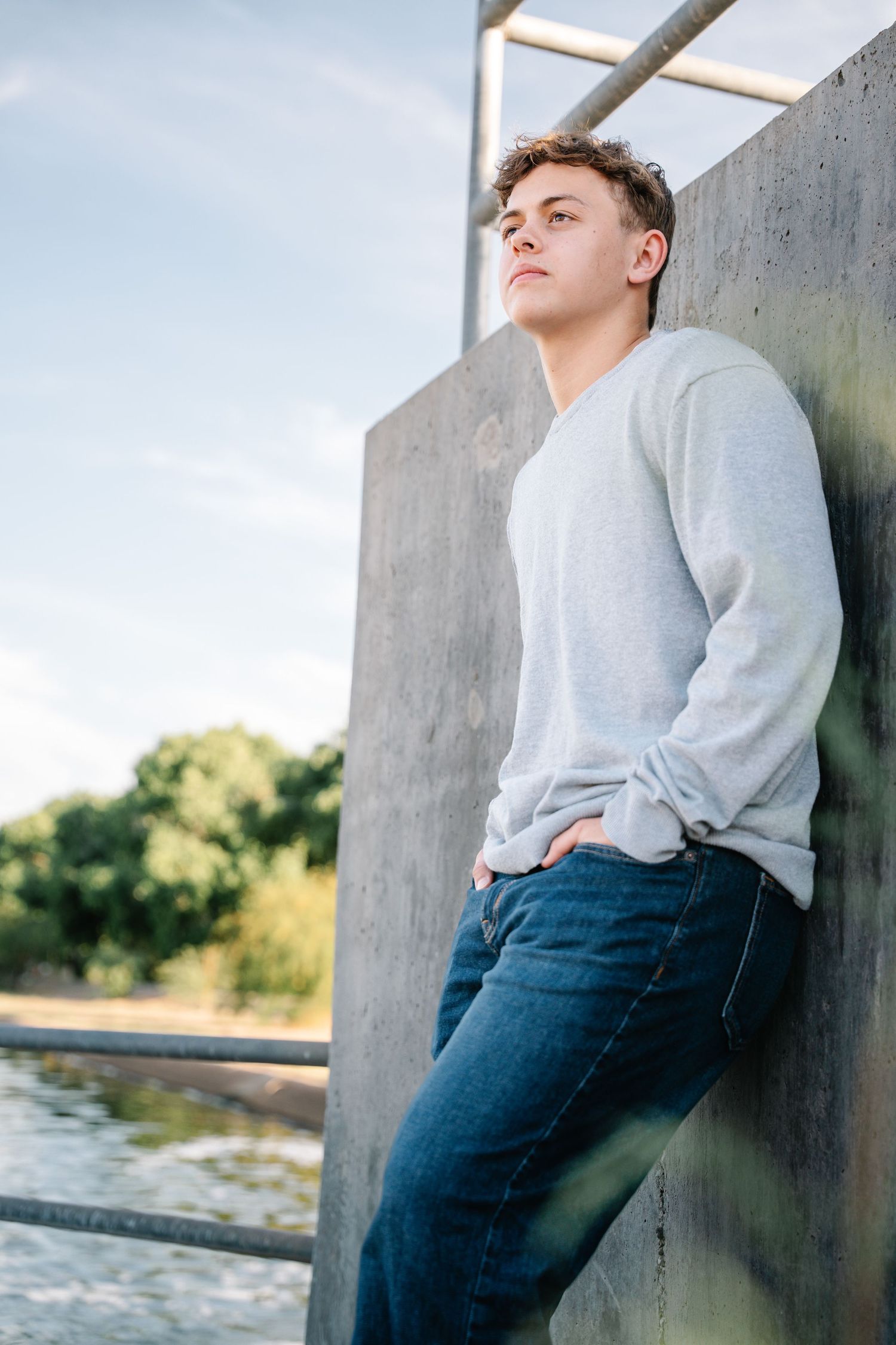 Des Moines Iowa senior portrait photographer – confident teenage boy in white shirt leaning against wall, serious and strong gaze.