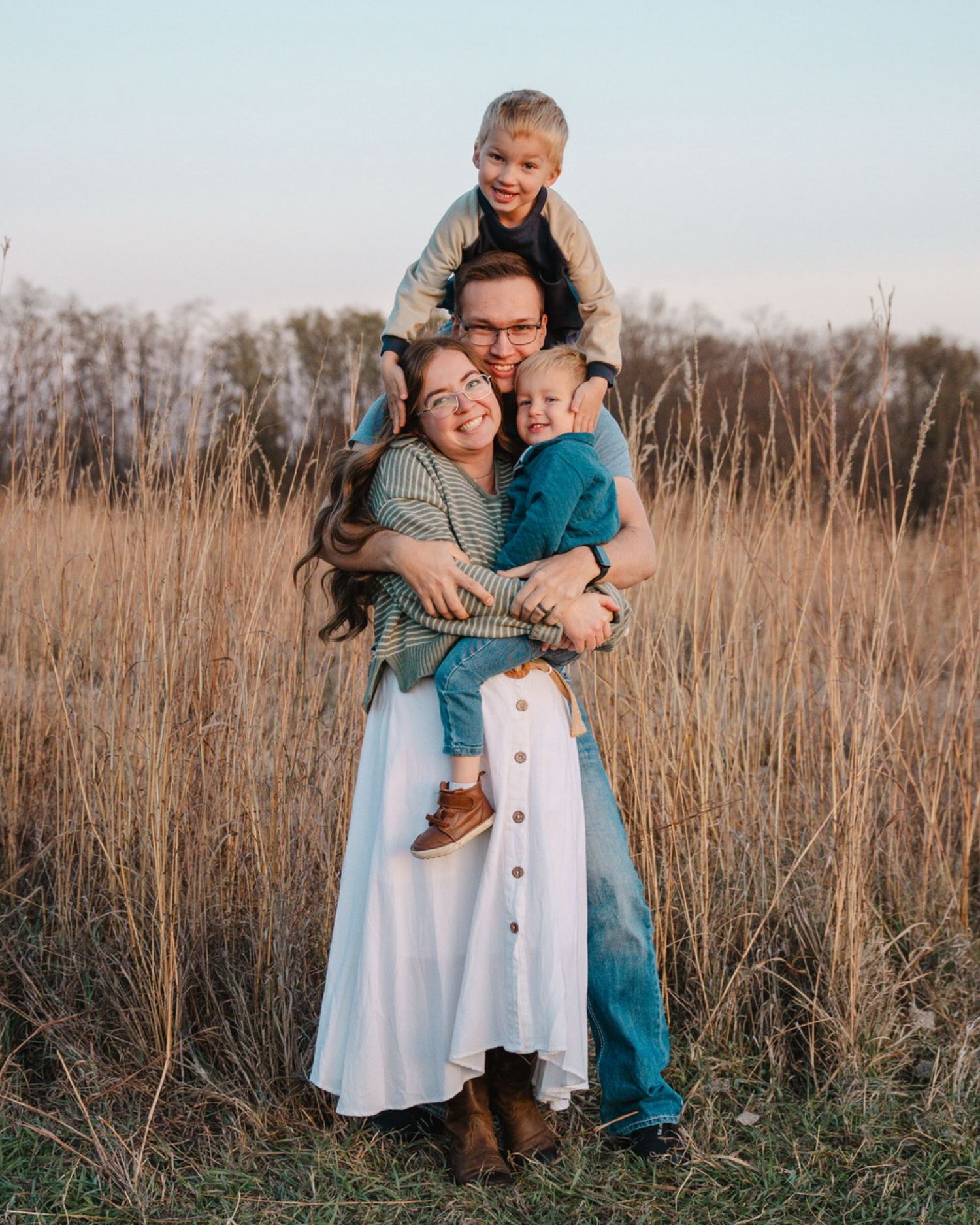 Cute young family stacked on top of one another seen embracing at golden hour near Saylorville Lake.