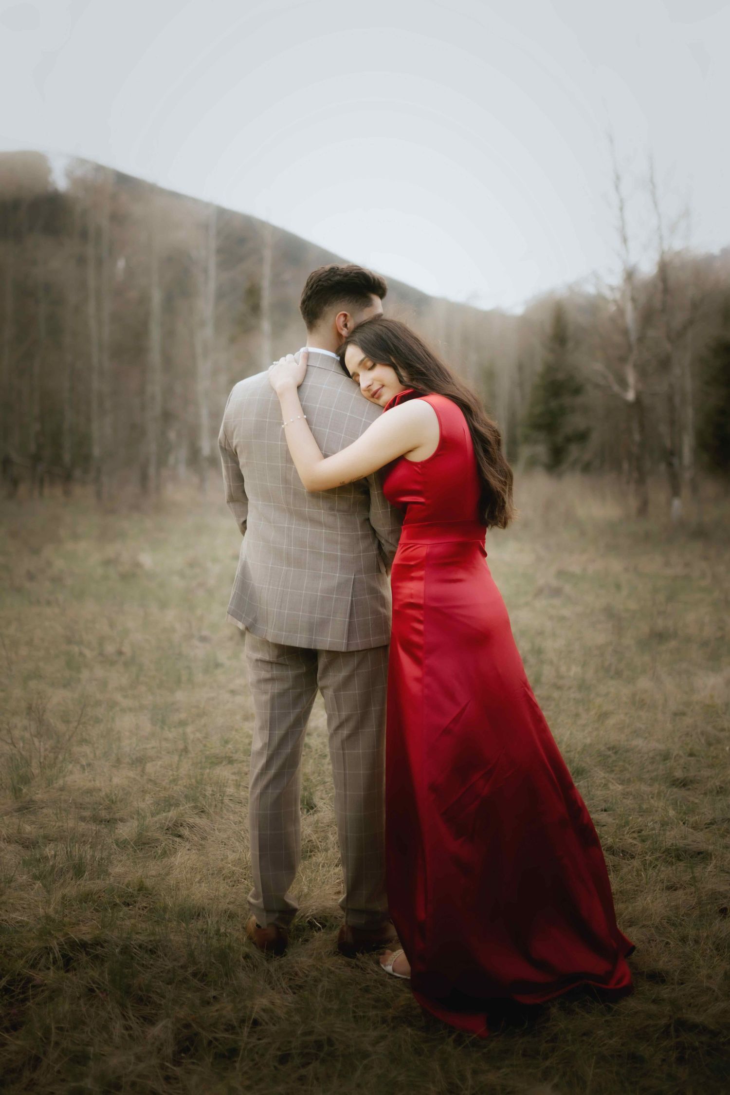 A couple in formal attire dances in a field, with the woman wearing a flowing red dress.
Rockies Couple Shoot