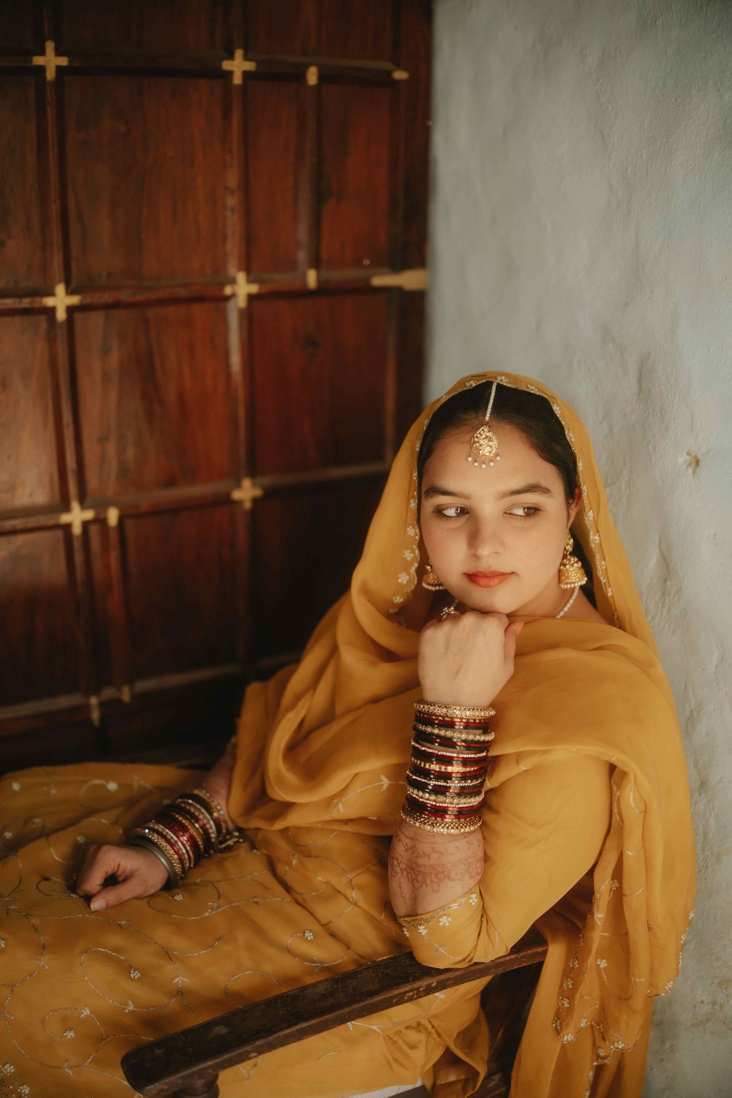 Traditional South Asian attire featuring yellow dupatta and bangles in indoor setting.
Traditional Punjabi bride