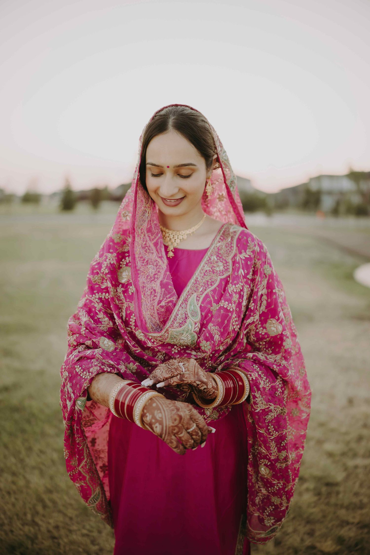 Bride in magenta and gold embroidered dupatta showing traditional henna designs.
choora Ceremony