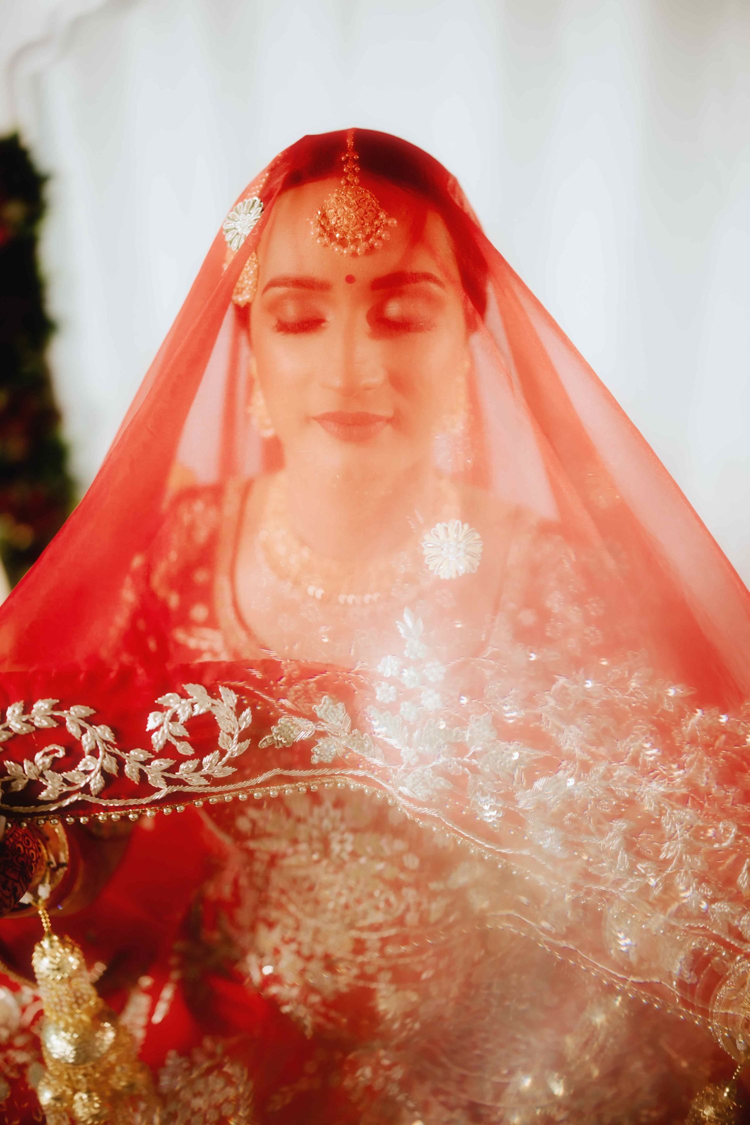 Intricate bridal veil with embroidered details captured through a red translucent fabric.
Punjabi bride