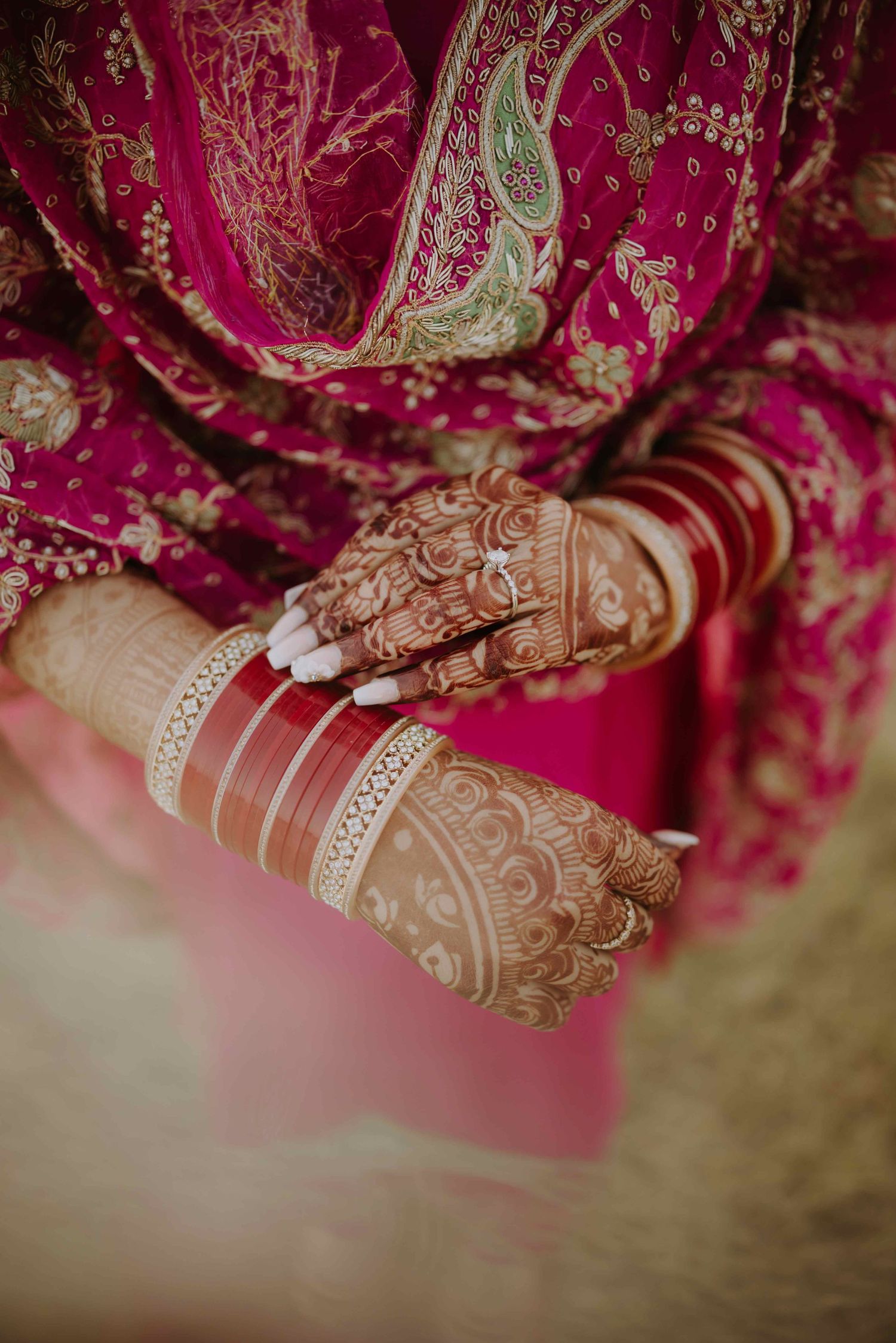 Detailed shot of bridal henna and bangles on hands with rich red fabric.
Choora ceremony