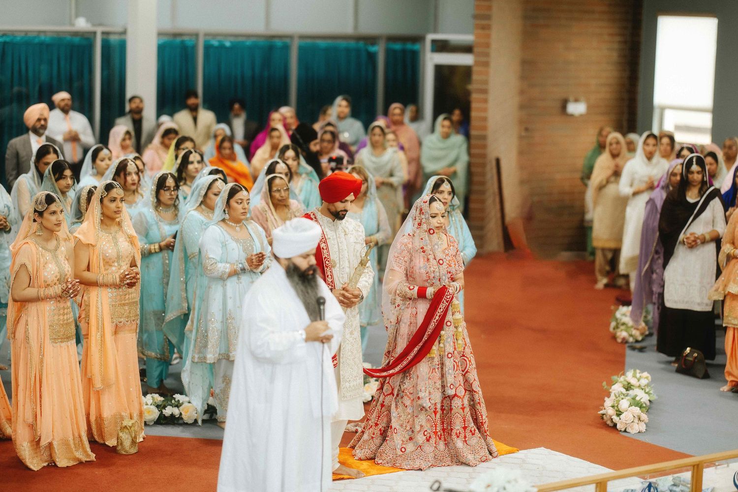A large gathering of wedding guests in traditional Indian attire standing in an indoor venue.
Sikh wedding photography