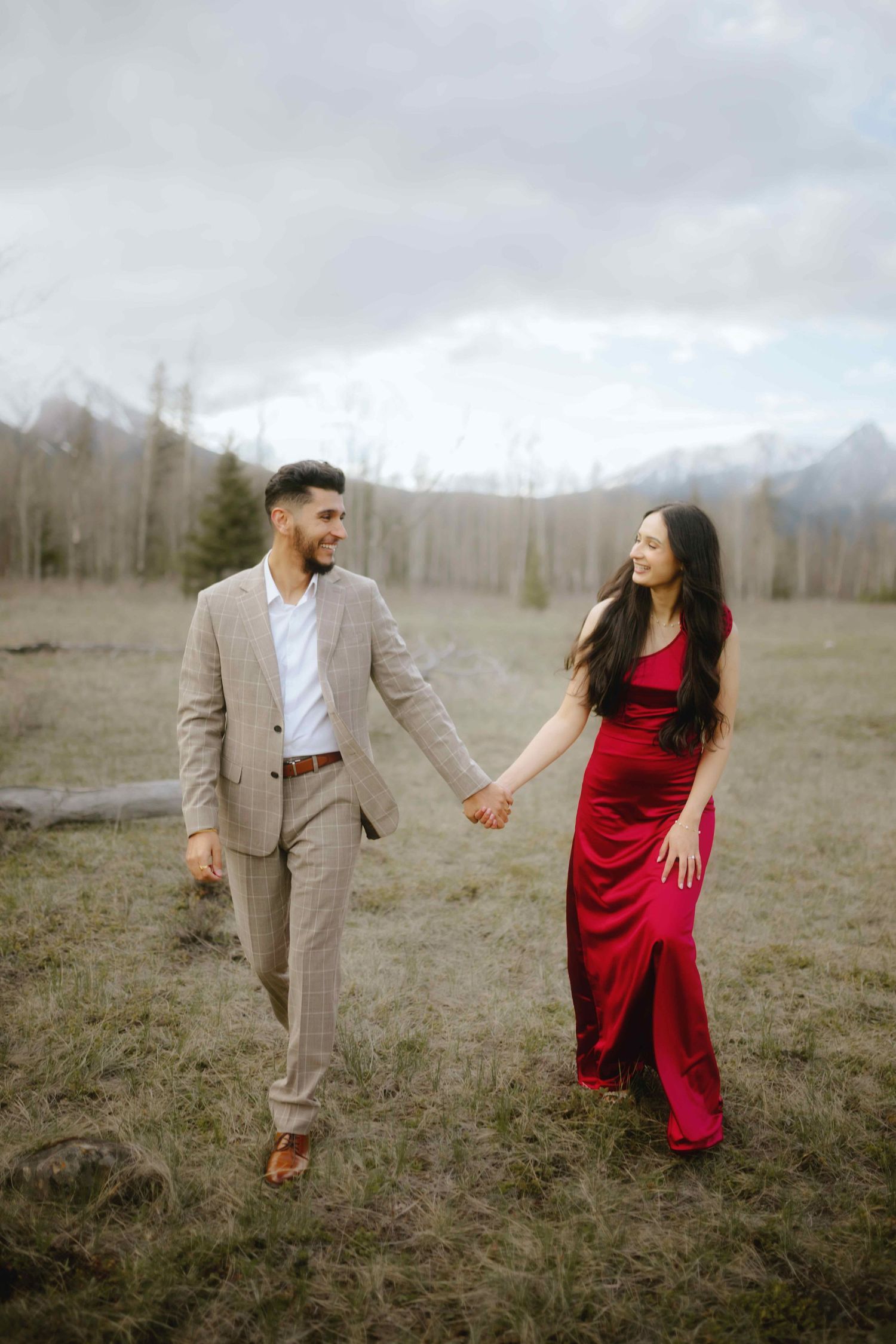 Playful engagement photoshoot in an open field featuring red dress and beige suit.
Banff Couple Shoot