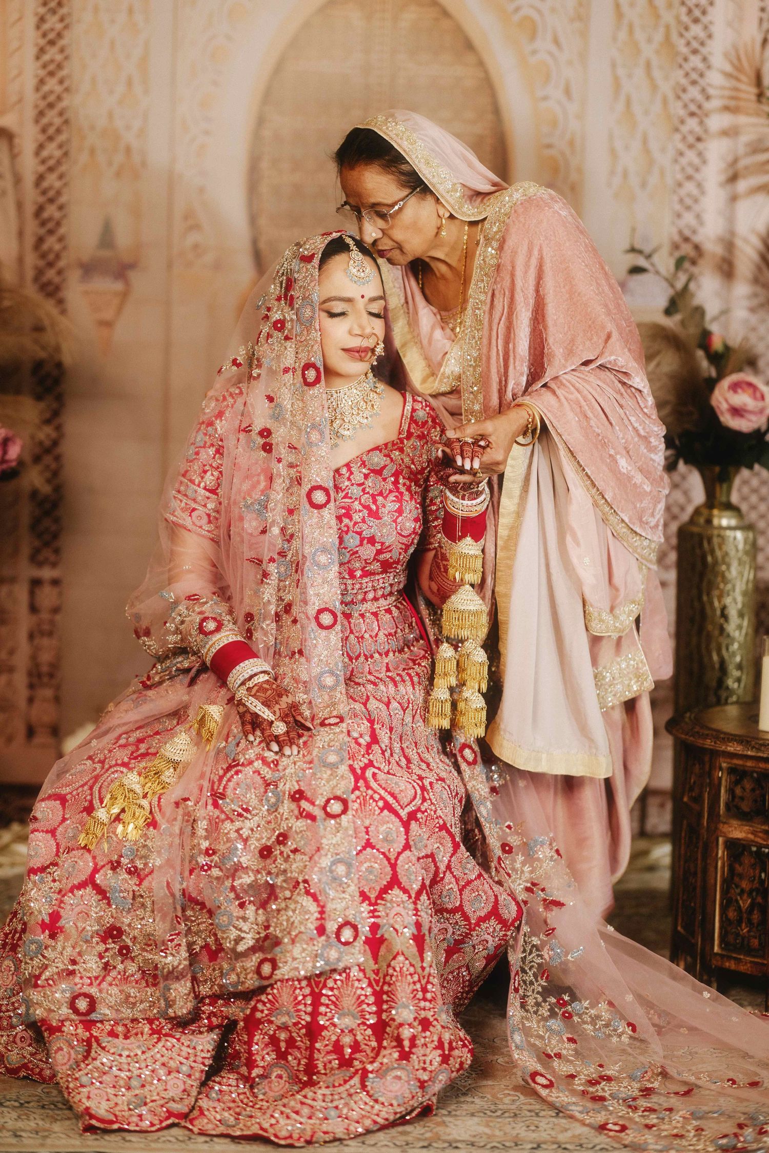 Two people in pink and red traditional South Asian wedding attire share an intimate moment.
Family portraits
