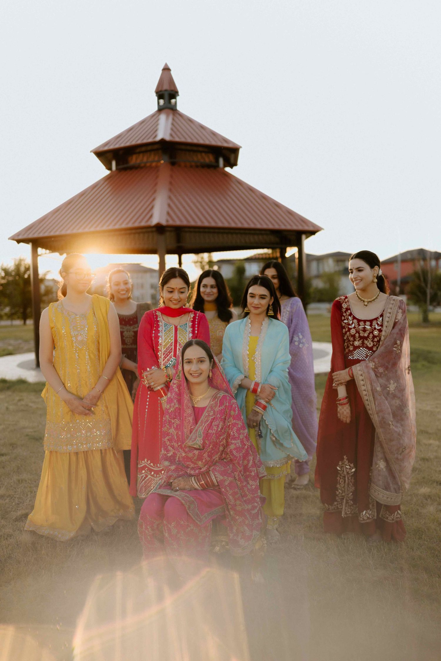 Group photo of wedding party in colorful traditional South Asian attire at gazebo during sunset.
Bridesmaids