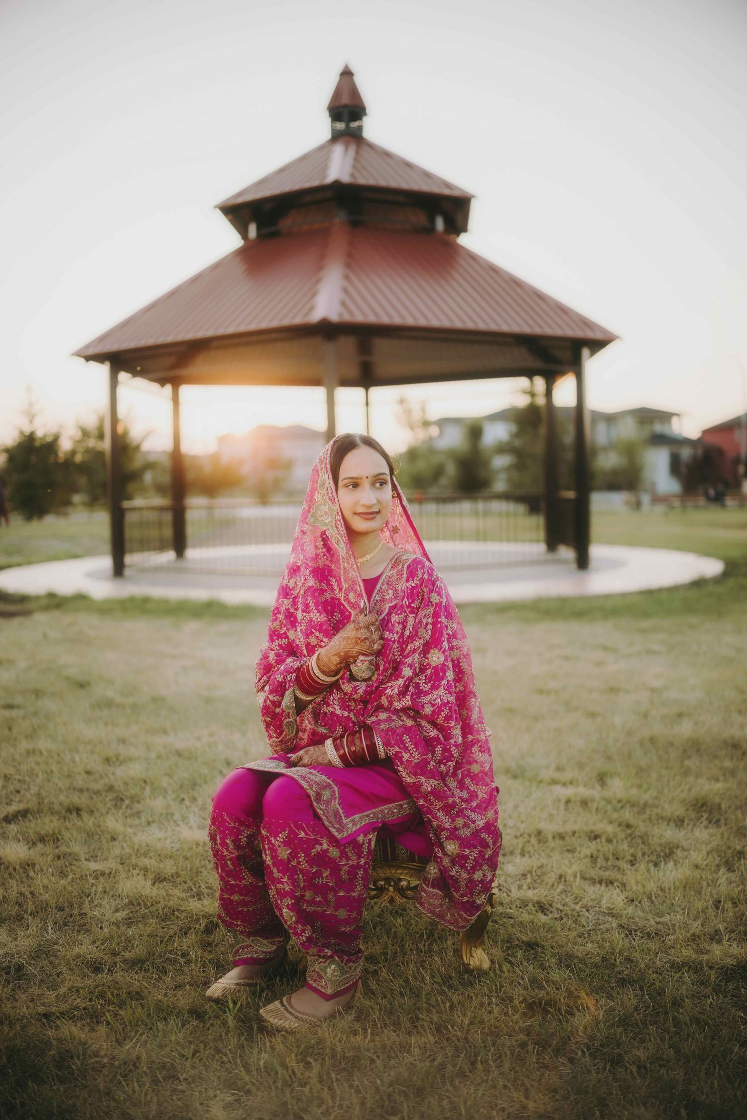 Traditional South Asian outfit in bright magenta against gazebo at sunset.
Bride to be
