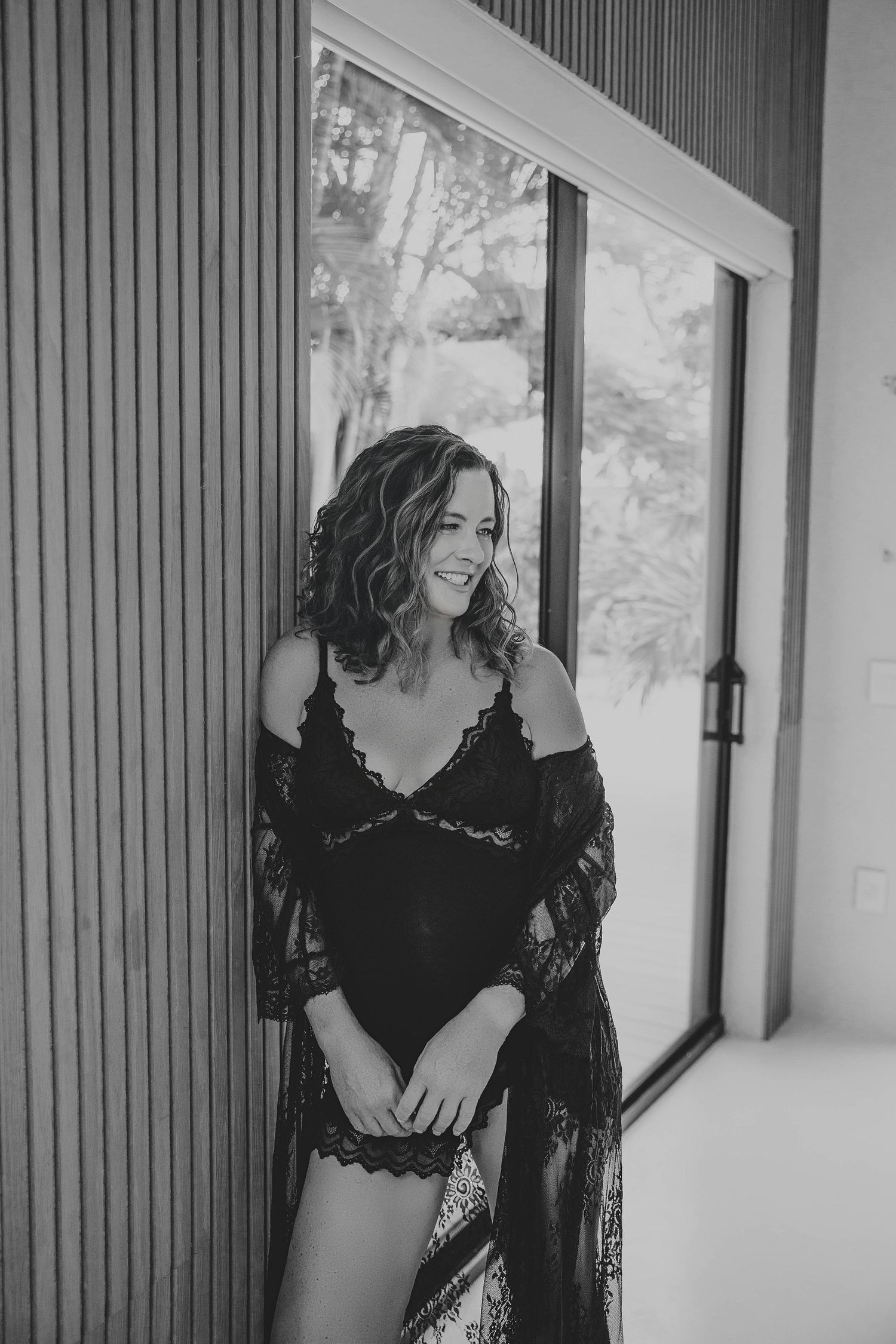 black-and-white portrait of a woman posing beside a studio window