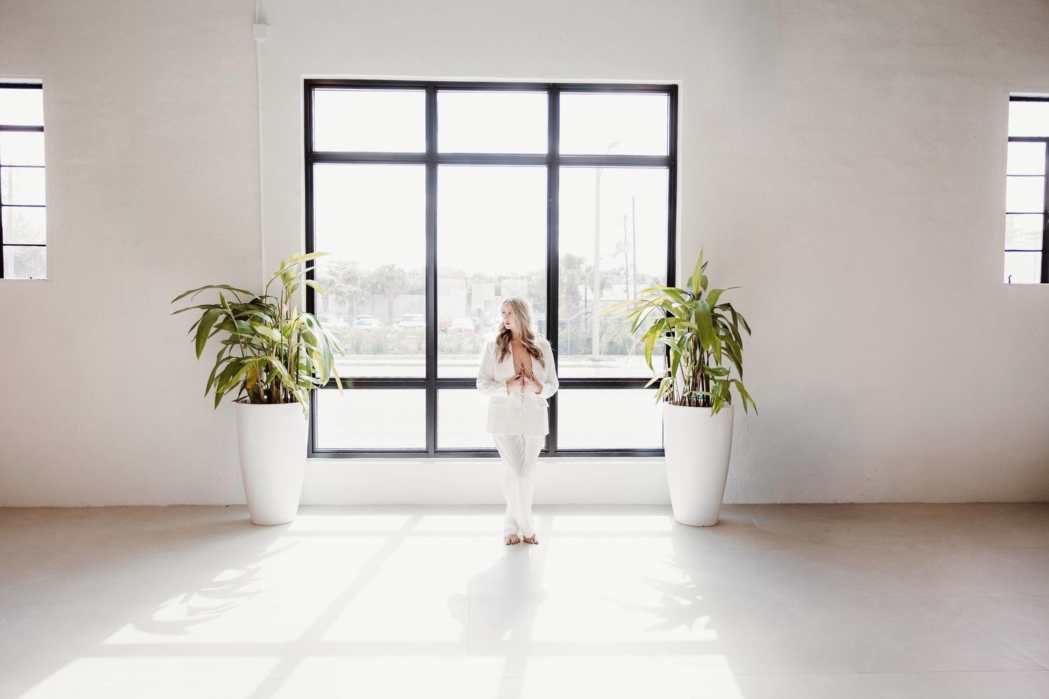 Woman posing beside a large window in a bright Sarasota Boudior Studio