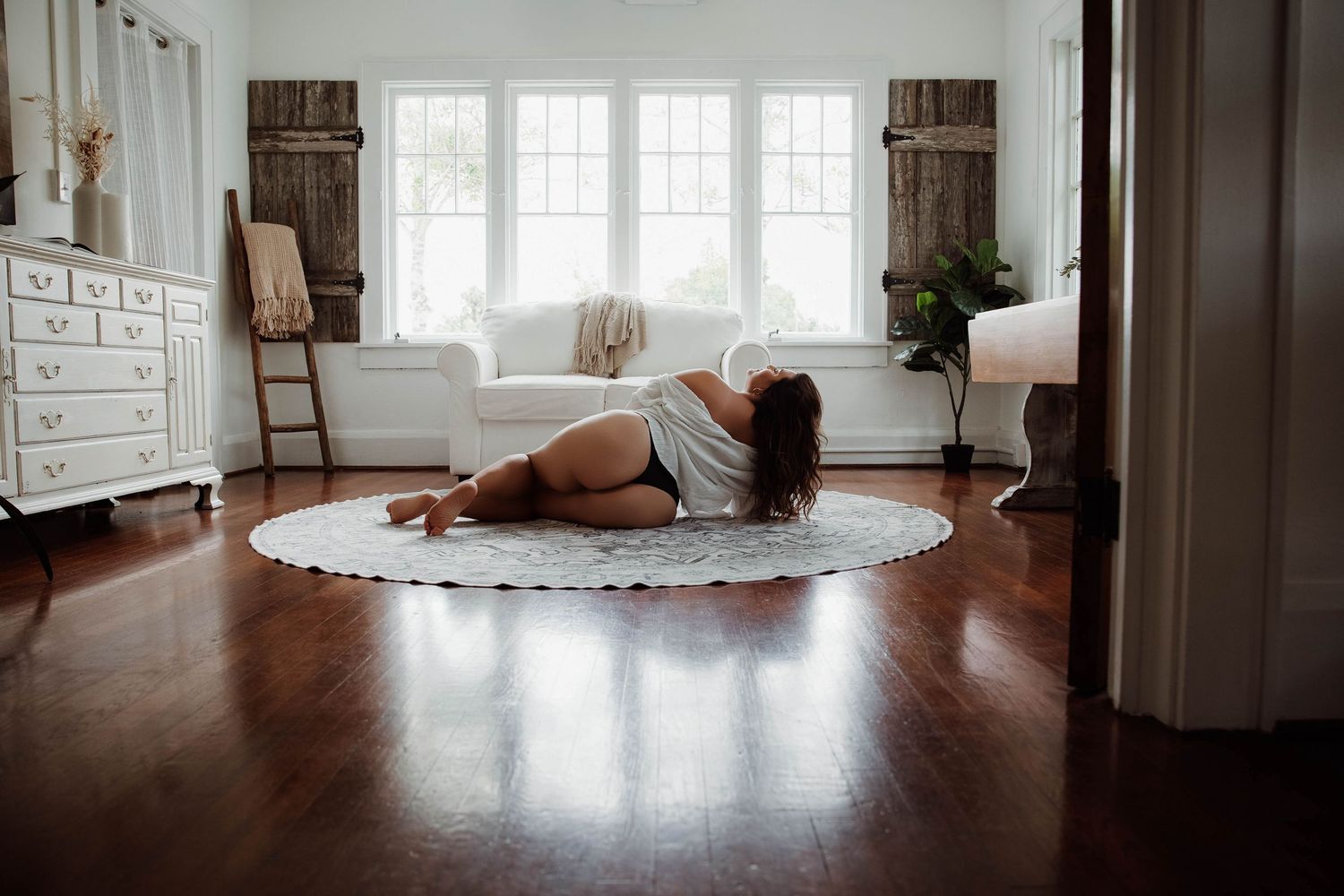 Portrait of a women Laying on the floor facing a window durning a boudoir session