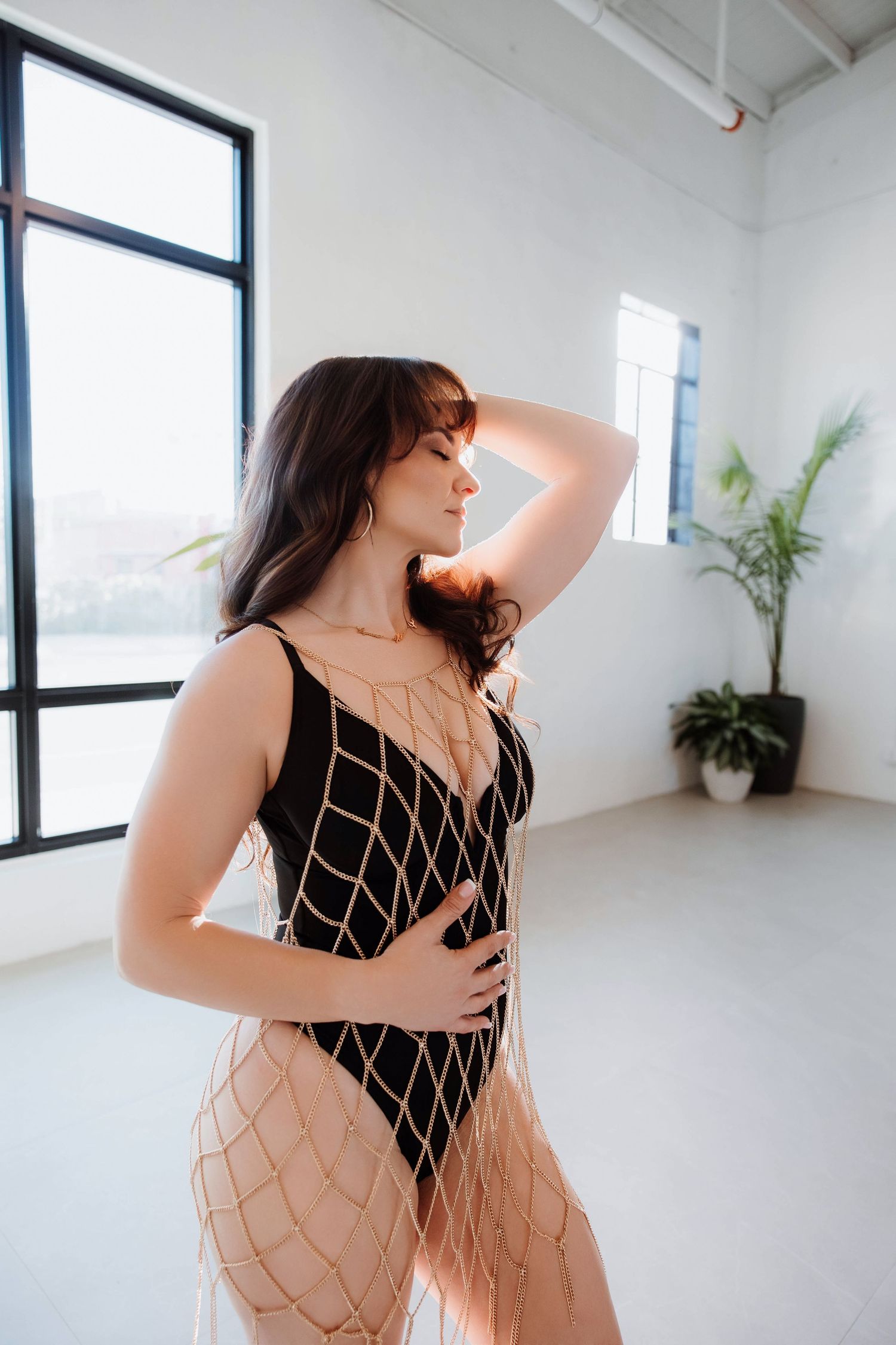 woman wearing a gold chain dress posing in a modern boudoir studio in Bradenton FL