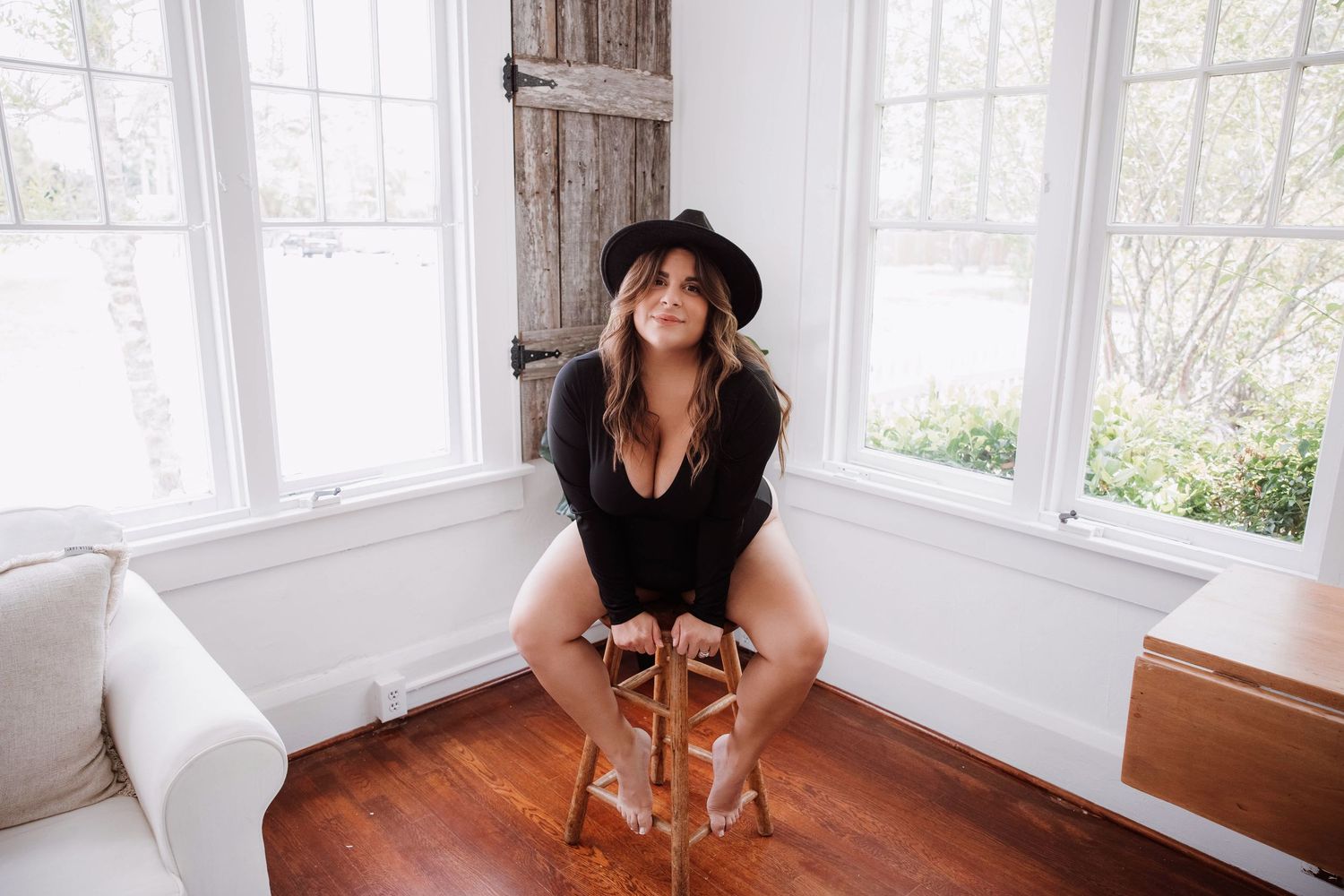 woman sitting on a stool durning a boudoir session in a modern home studio