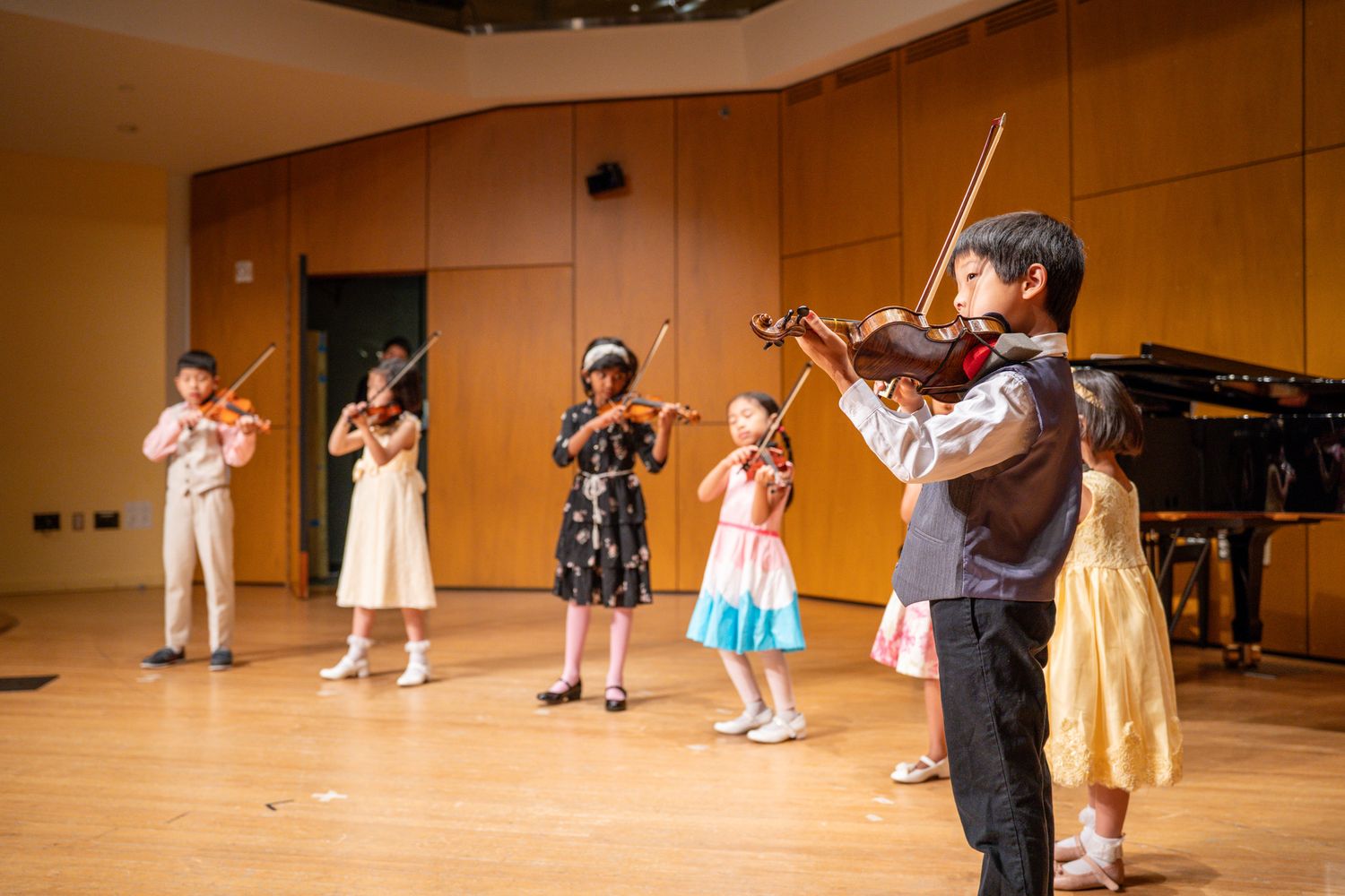 Young students performing together on violins during a music recital.