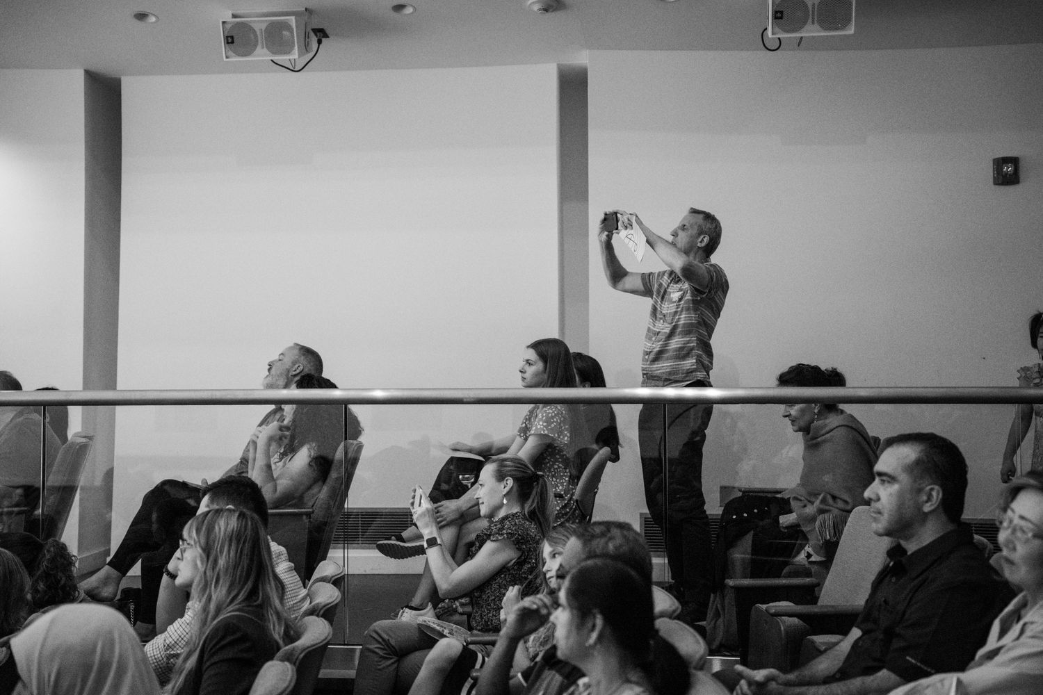 Black and white photo of audience members capturing moments during a children's music recital.