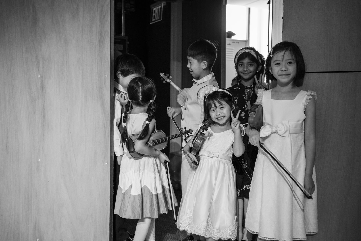 Black and white photo of young violin students waiting backstage before a performance.