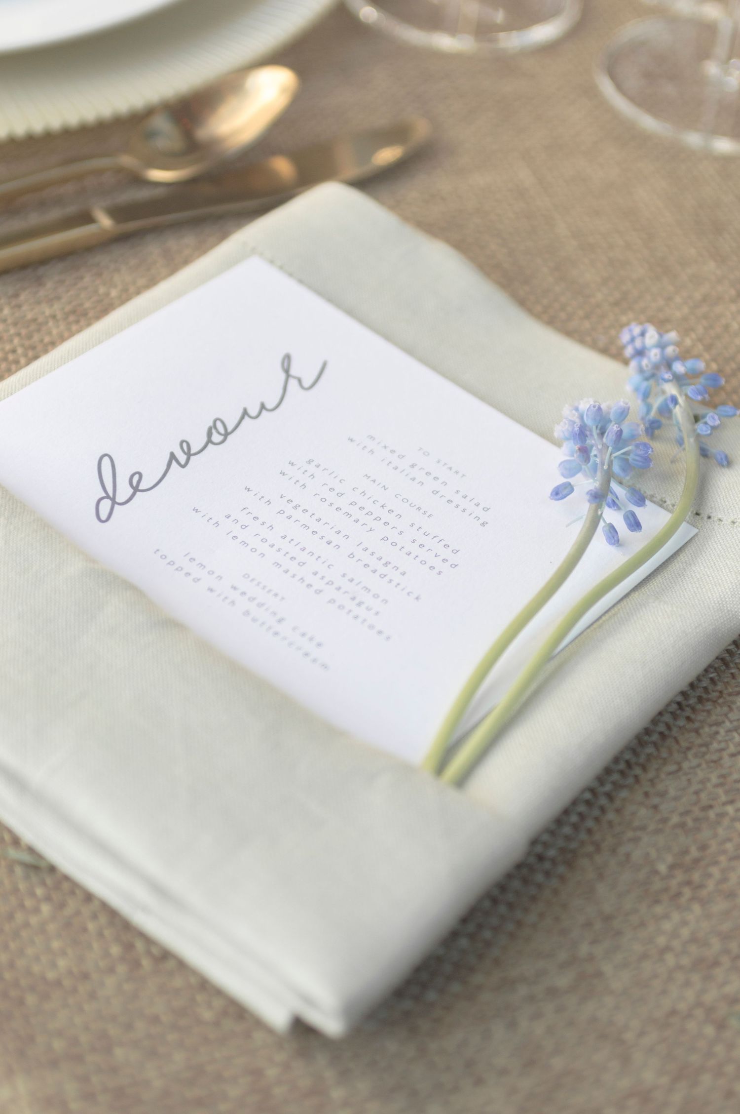 Elegant wedding place setting with a folded napkin, handwritten name card, and lavender sprig.