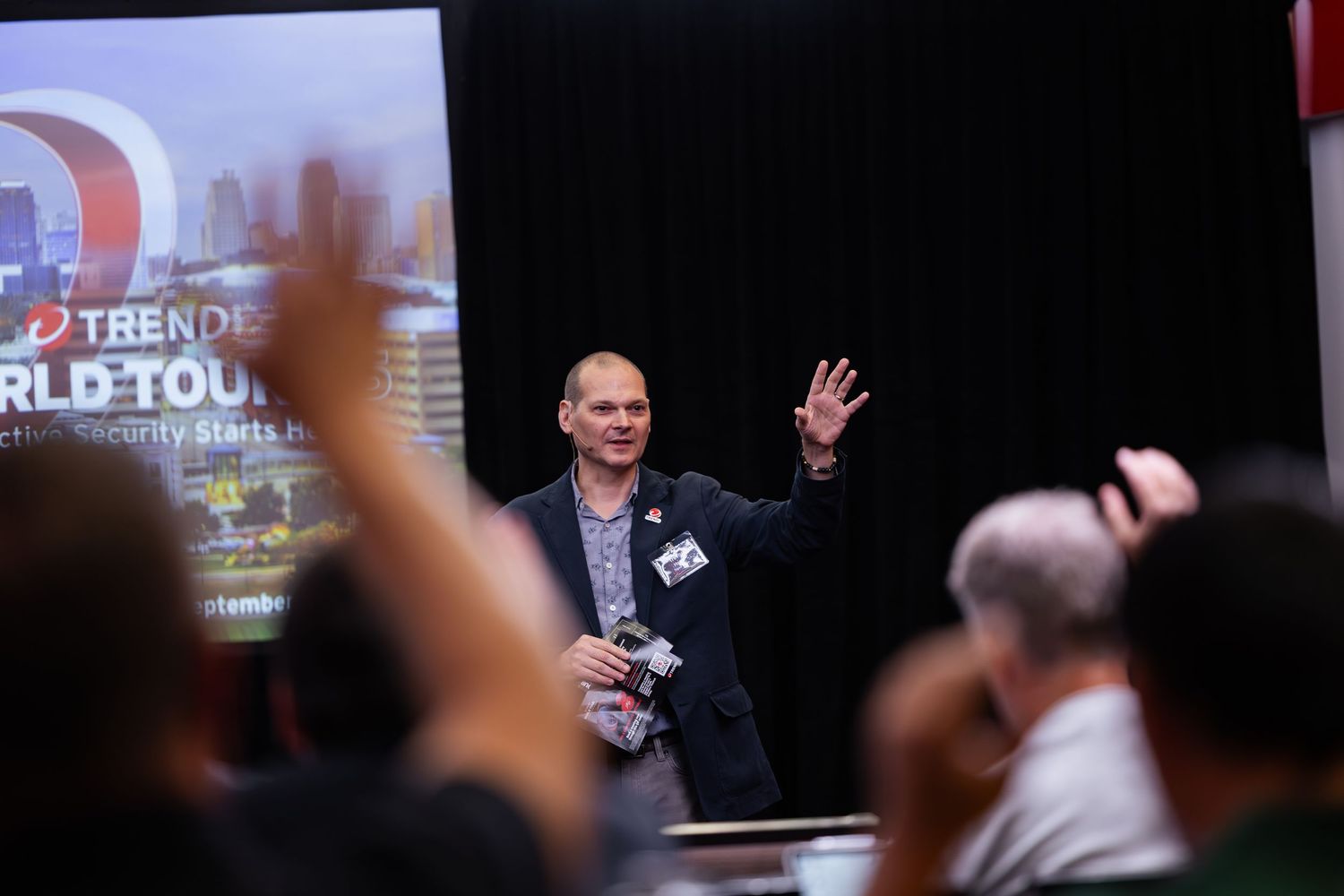 Presenter waving to audience at a Trend Micro World Tour cybersecurity conference event.