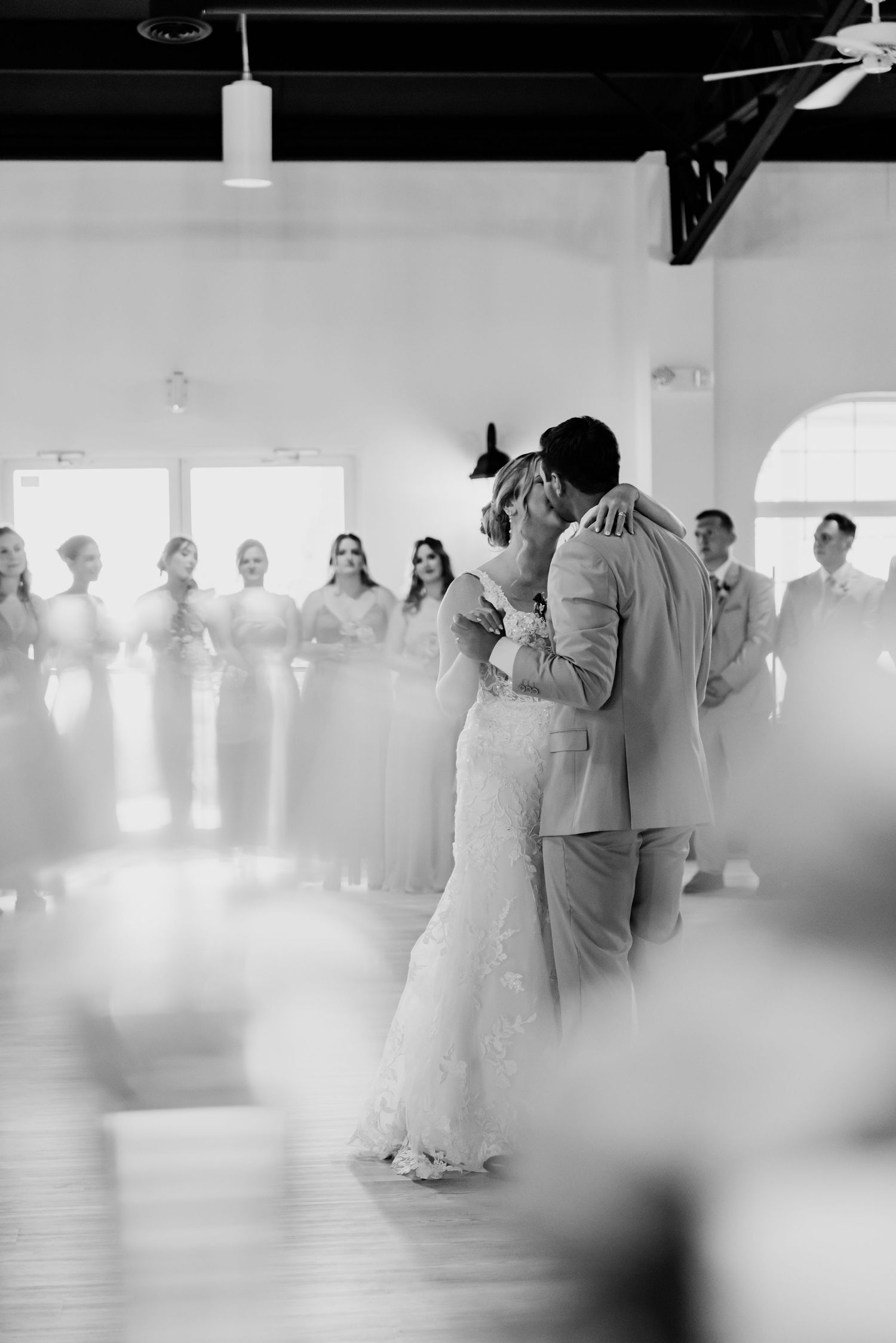 Bride and groom share intimate first dance embrace in black and white wedding reception photo.