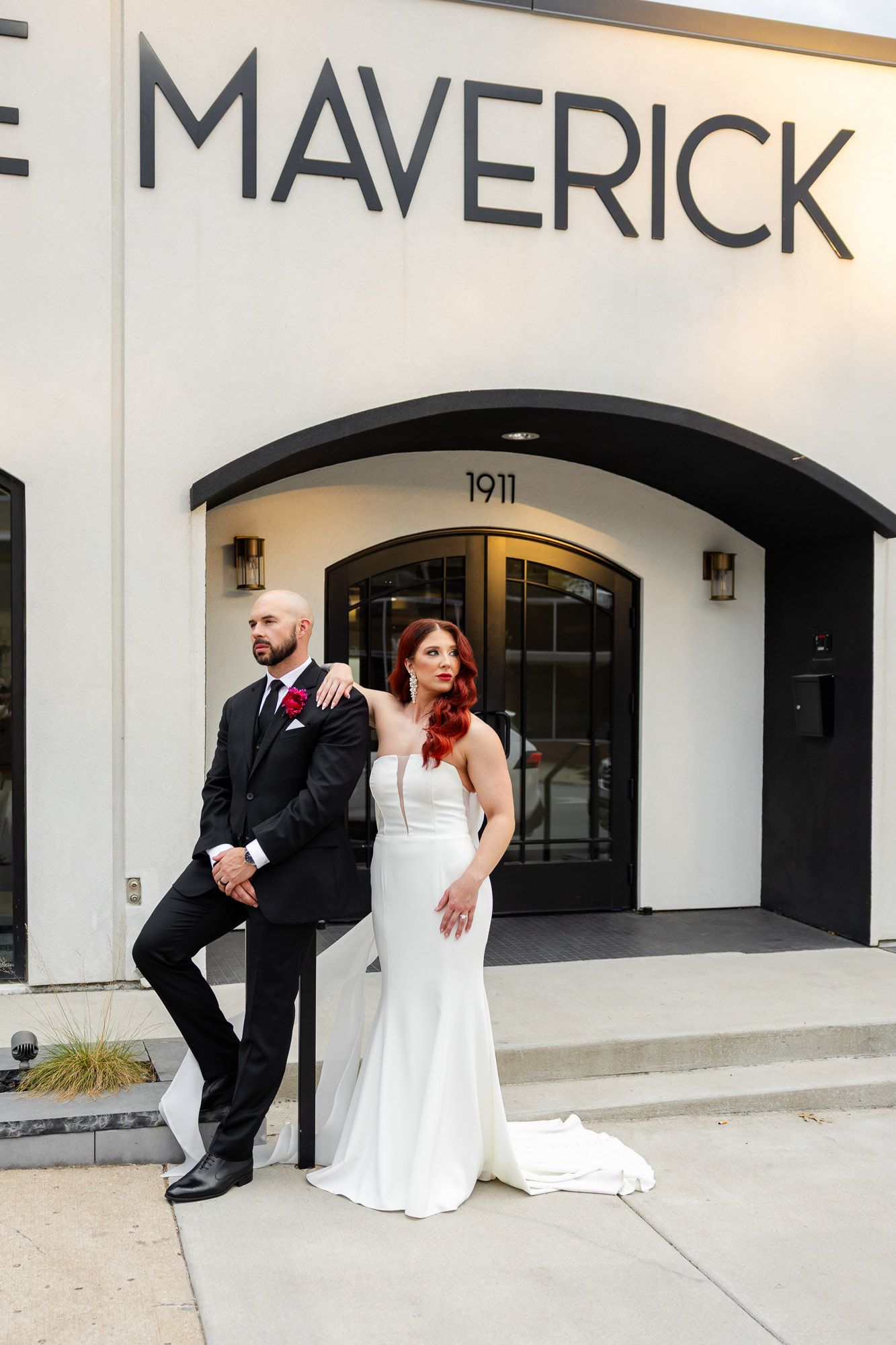 Stylish bride and groom pose confidently outside The Maverick venue at 1911.