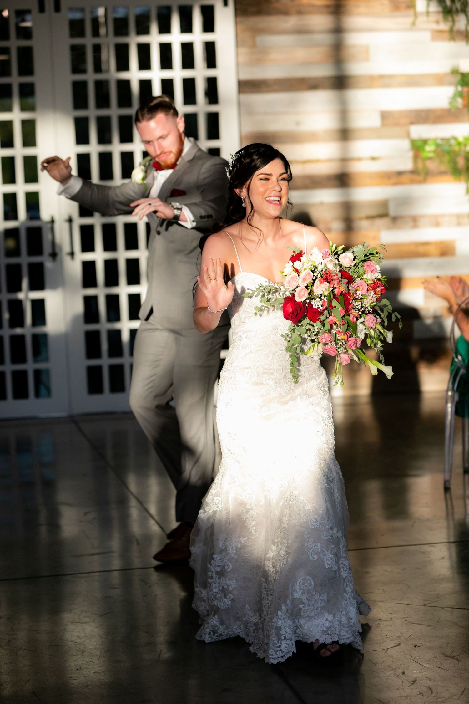 Excited newlyweds make a grand entrance at their wedding reception with a colorful bridal bouquet.
