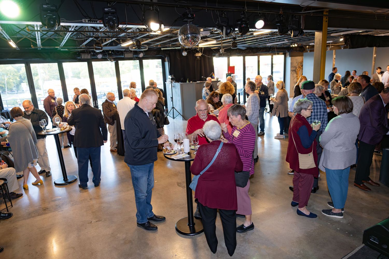 Large group of guests mingling at an indoor networking event with concrete floors.