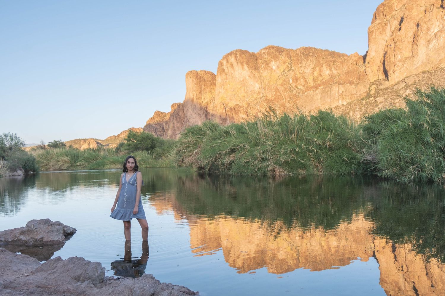 Rugged mountain landscape reflects in still waters at a desert oasis.