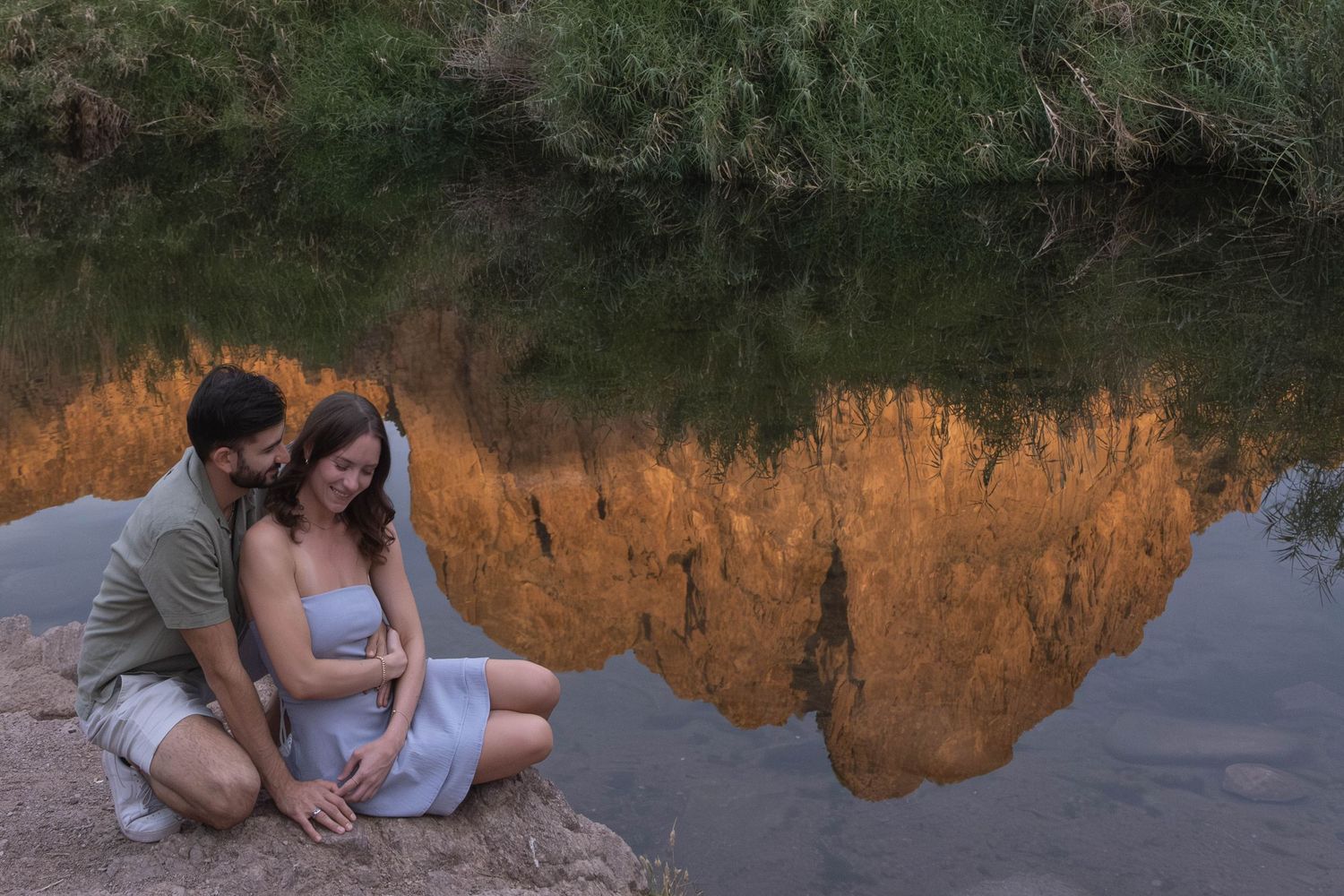 Desert mountain landscape reflected in still waters with a couple along the shore.