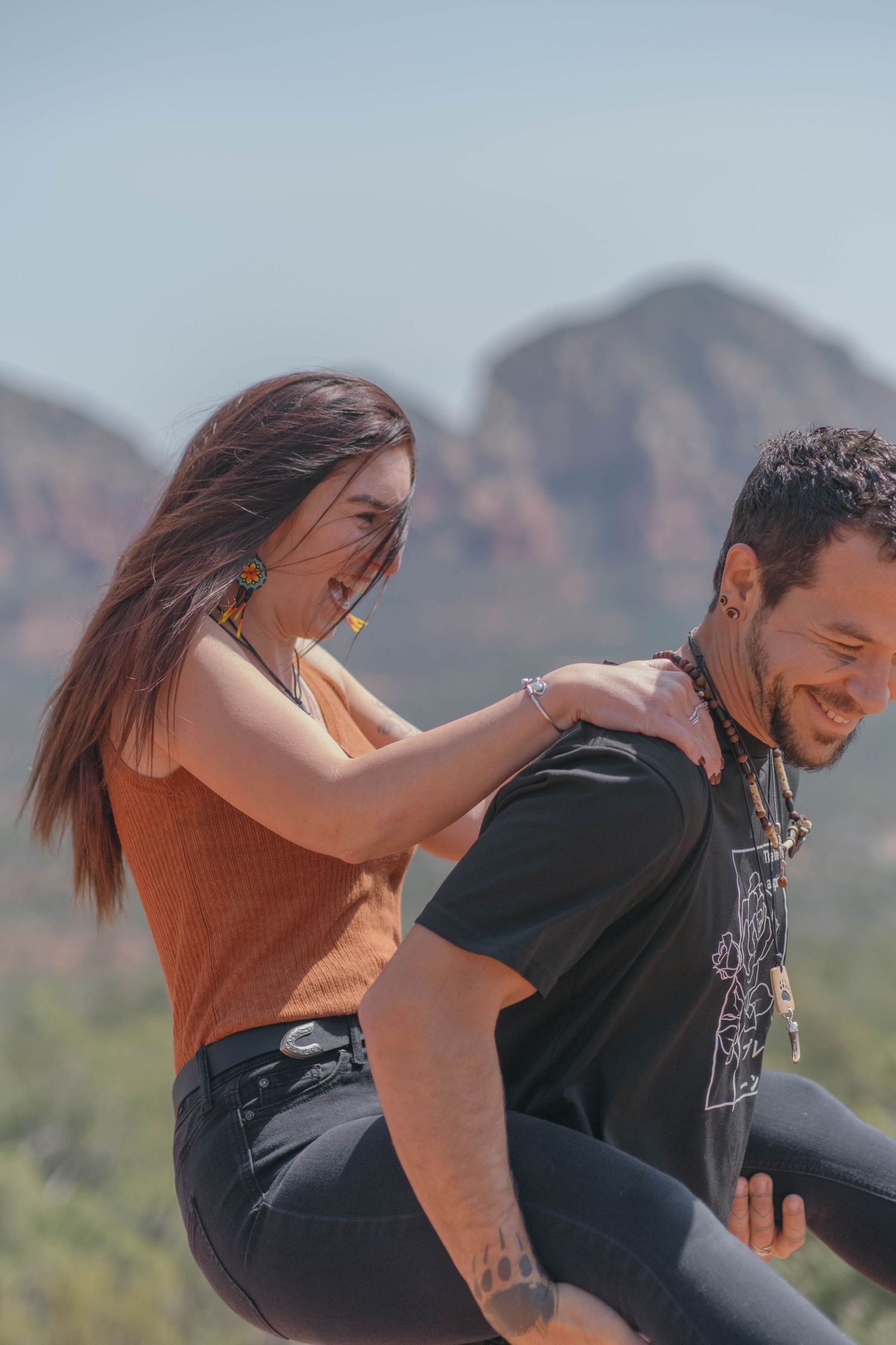 Partner piggybacking the other through the red rocks of Sedona, Arizona.