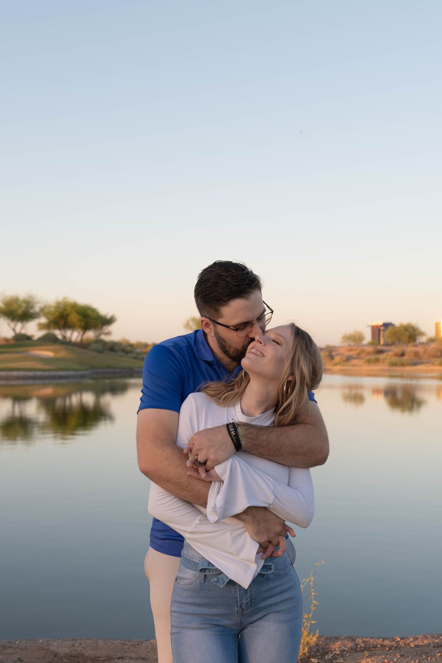 A tender embrace by the water during golden hour.