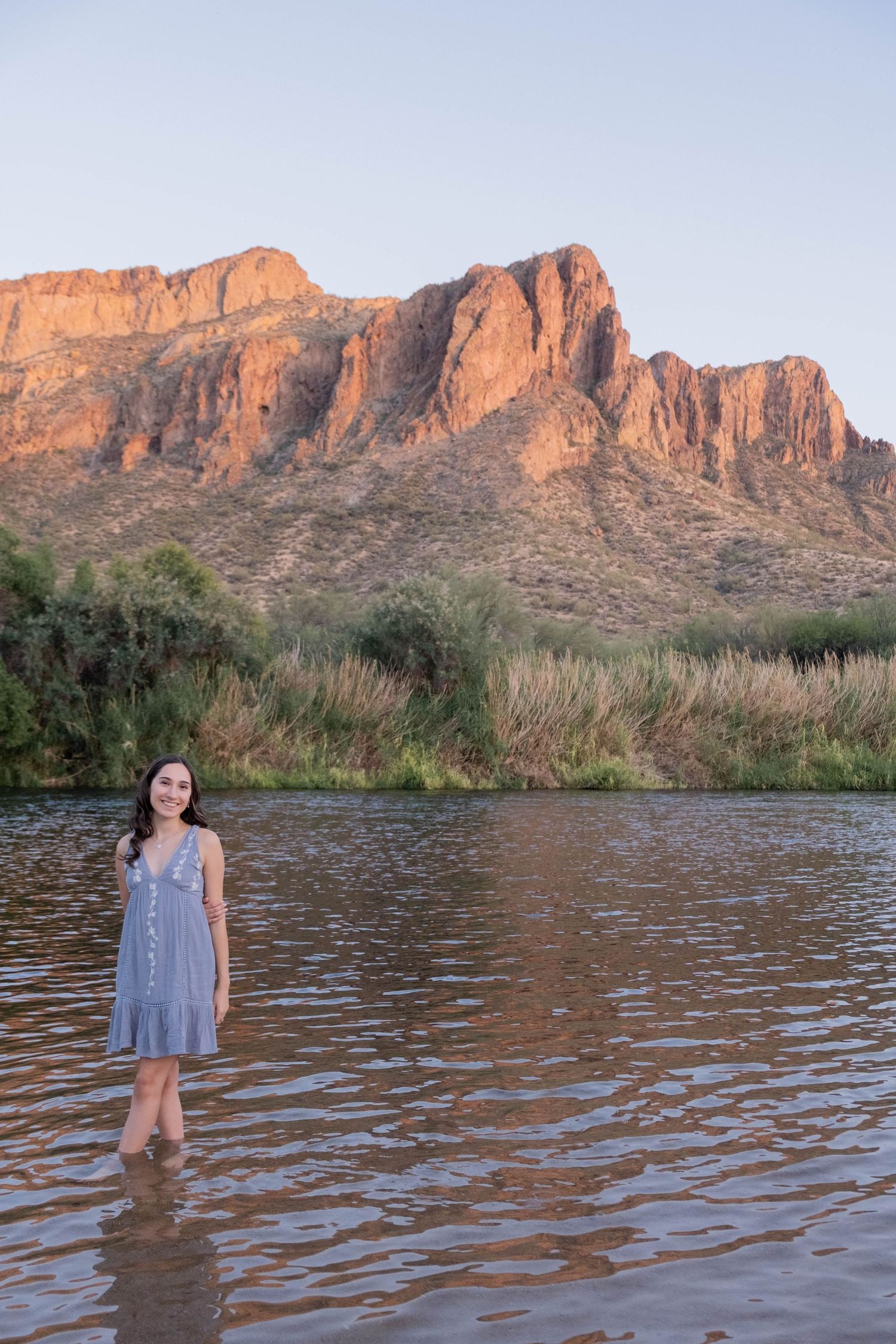 A scenic desert photo shoot at sunset featuring rugged mountains and water reflections in a desert lake.