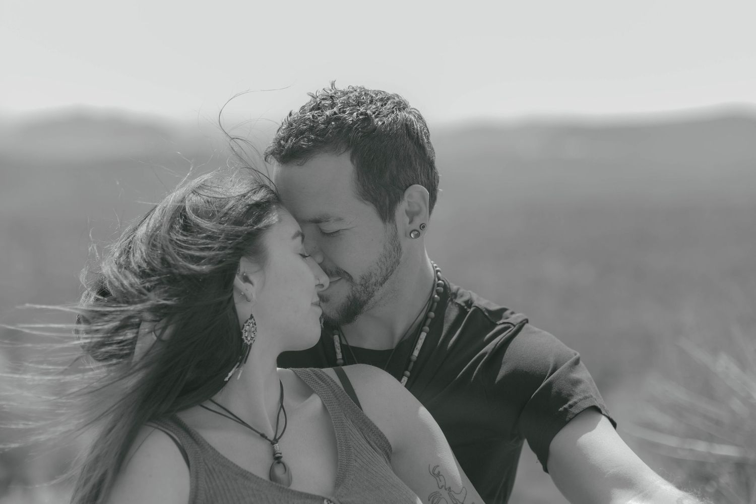 Couple embracing and kissing against dramatic desert mountain backdrop.