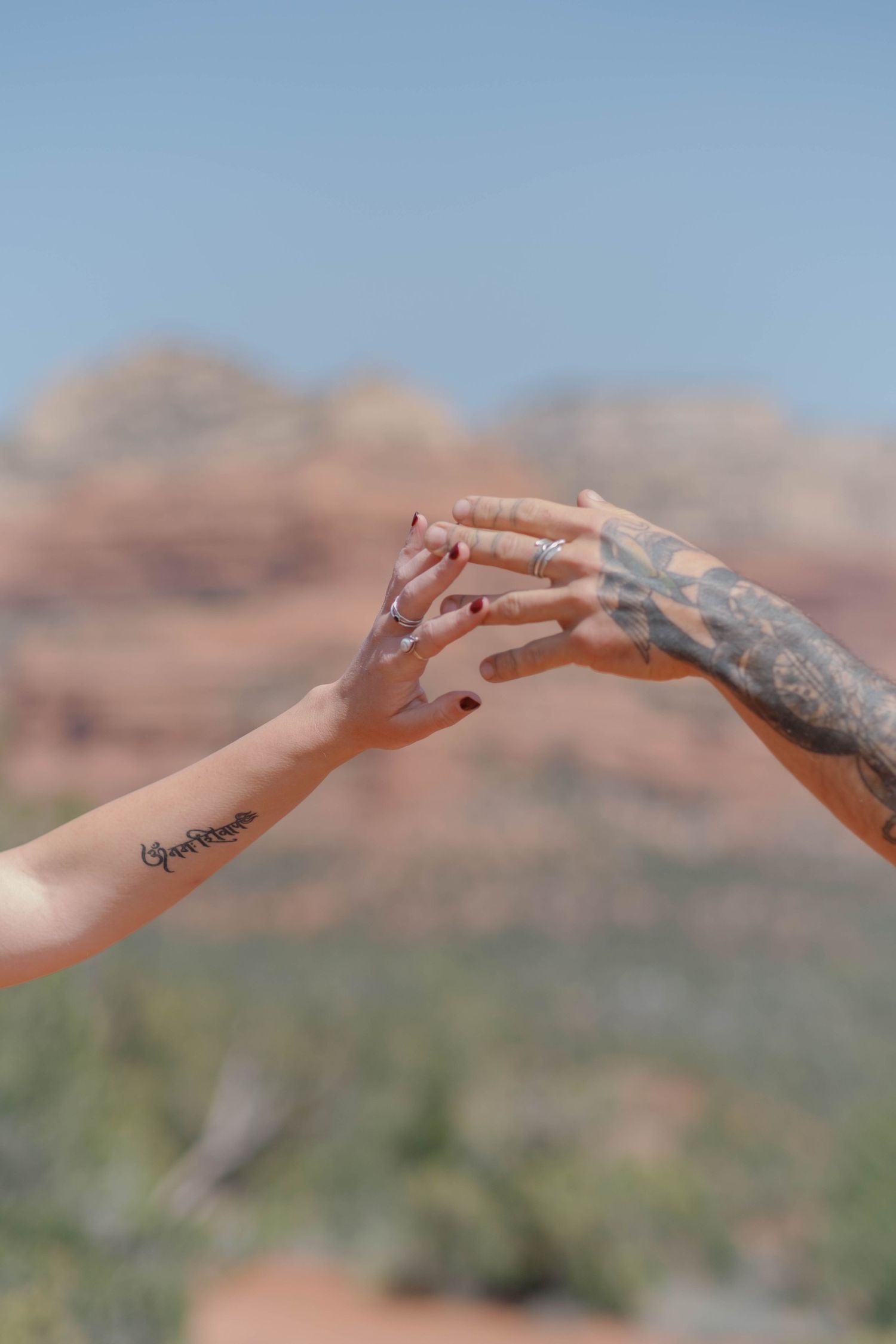 Couple playing with their hands in the red rock backdrop of Sedona, Arizona.
