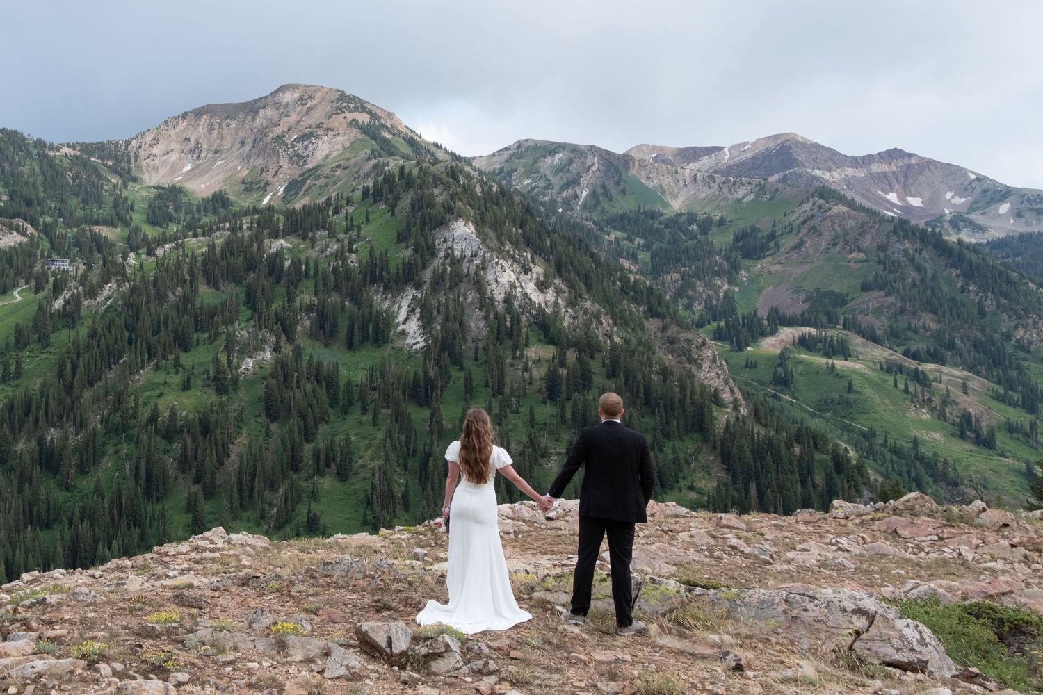 Scenic mountain wedding shoot in the rugged wilderness with stunning peaks and alpine forests in the background.