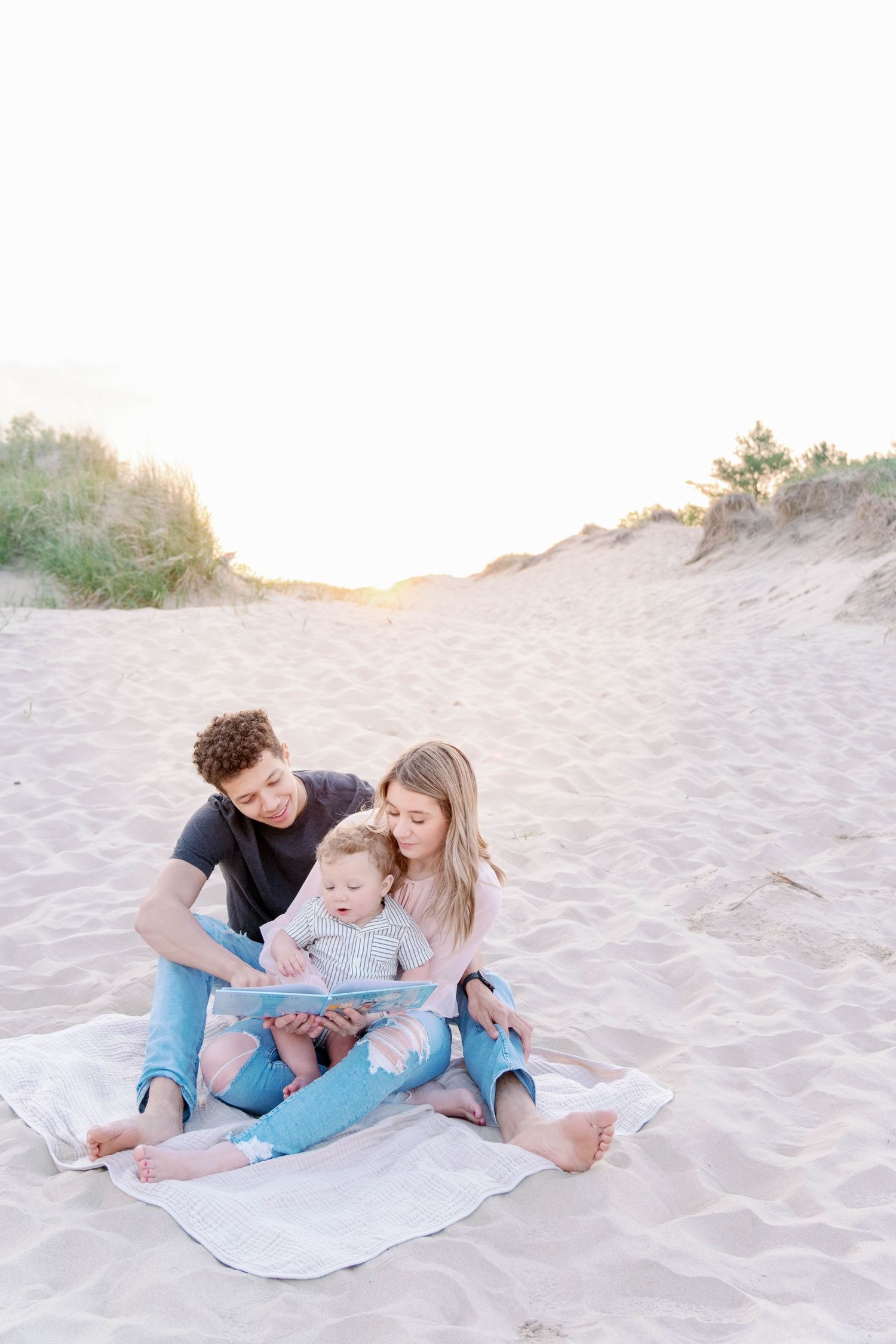 Heartfelt moment with a family reading a book on the beach.
