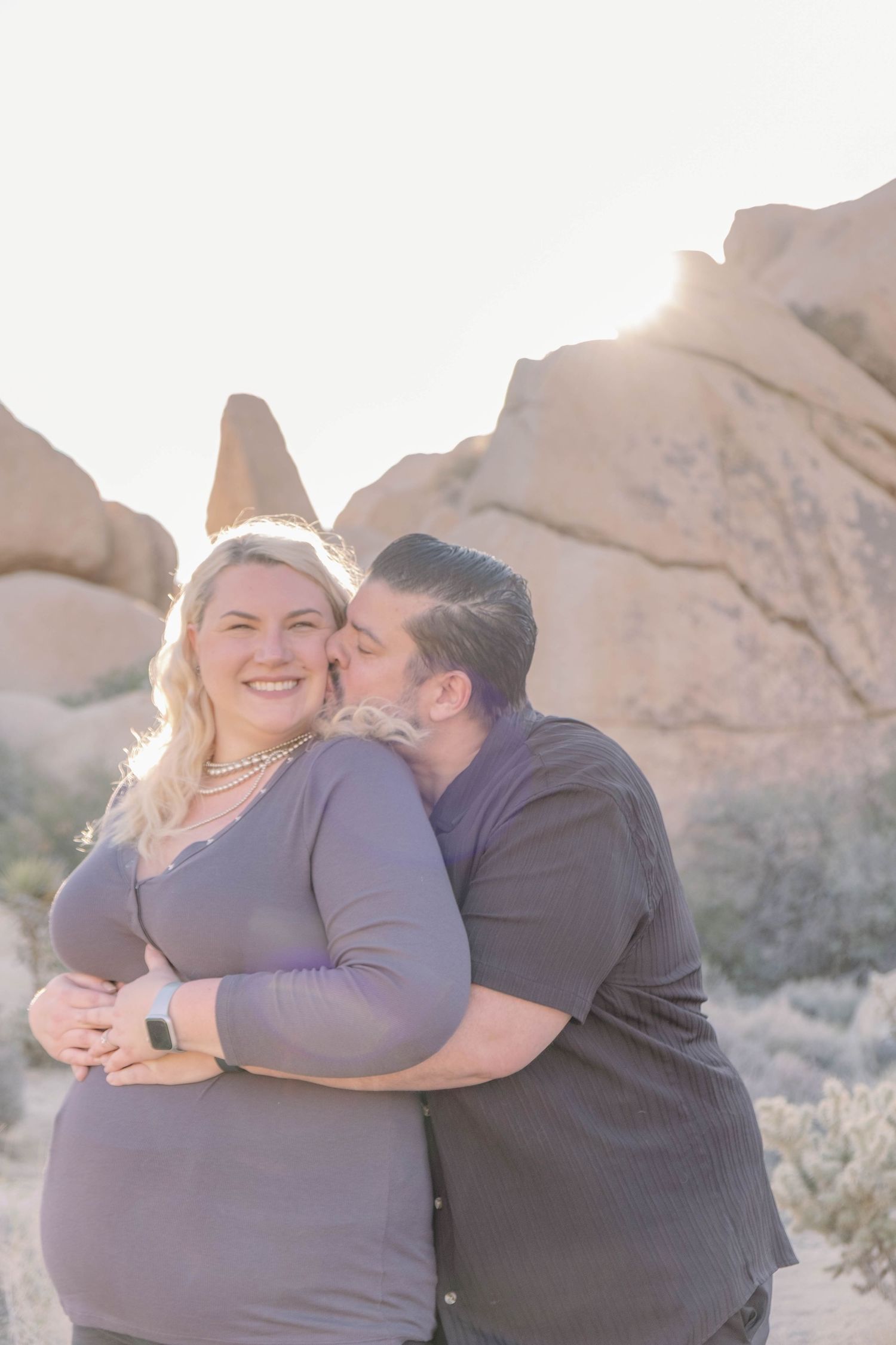 A joyful couple embraces and laughs together against a desert mountain backdrop.