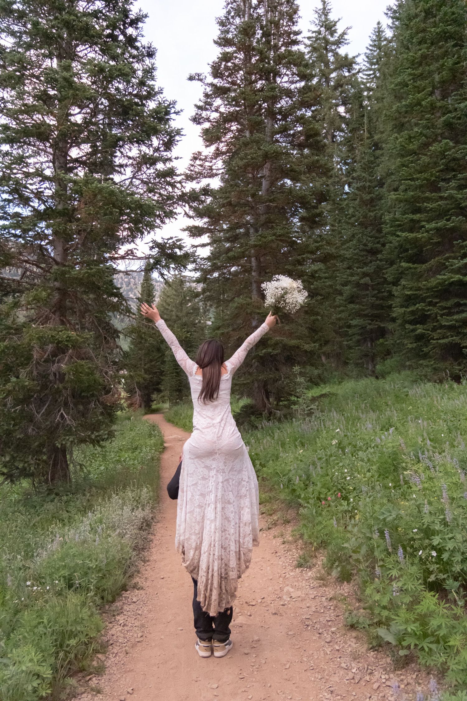 A series of photos showing someone in a flowy dress walking on a mountain hiking trail surrounded by evergreen trees.