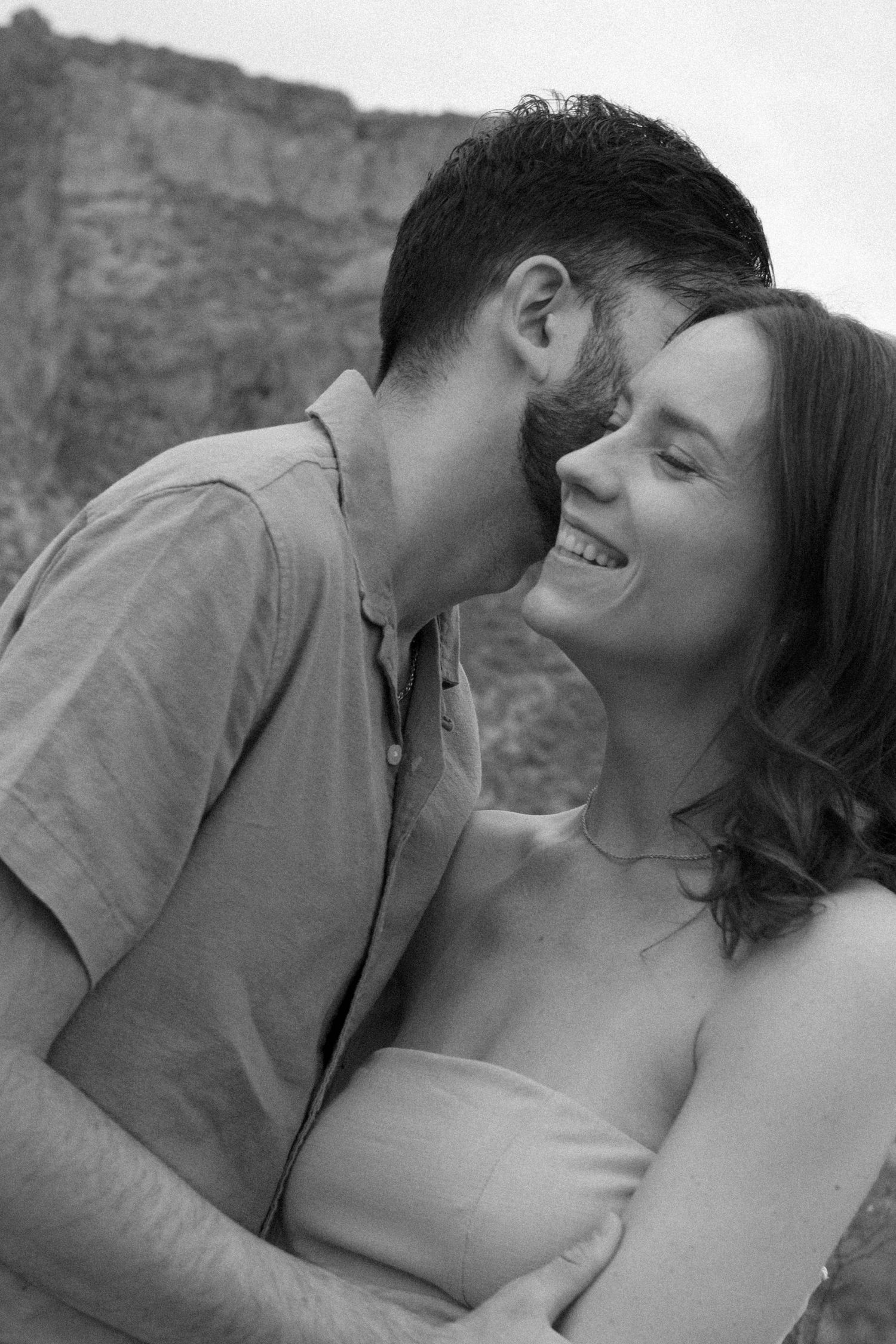 An intimate black and white portrait of a couple sharing a tender moment.