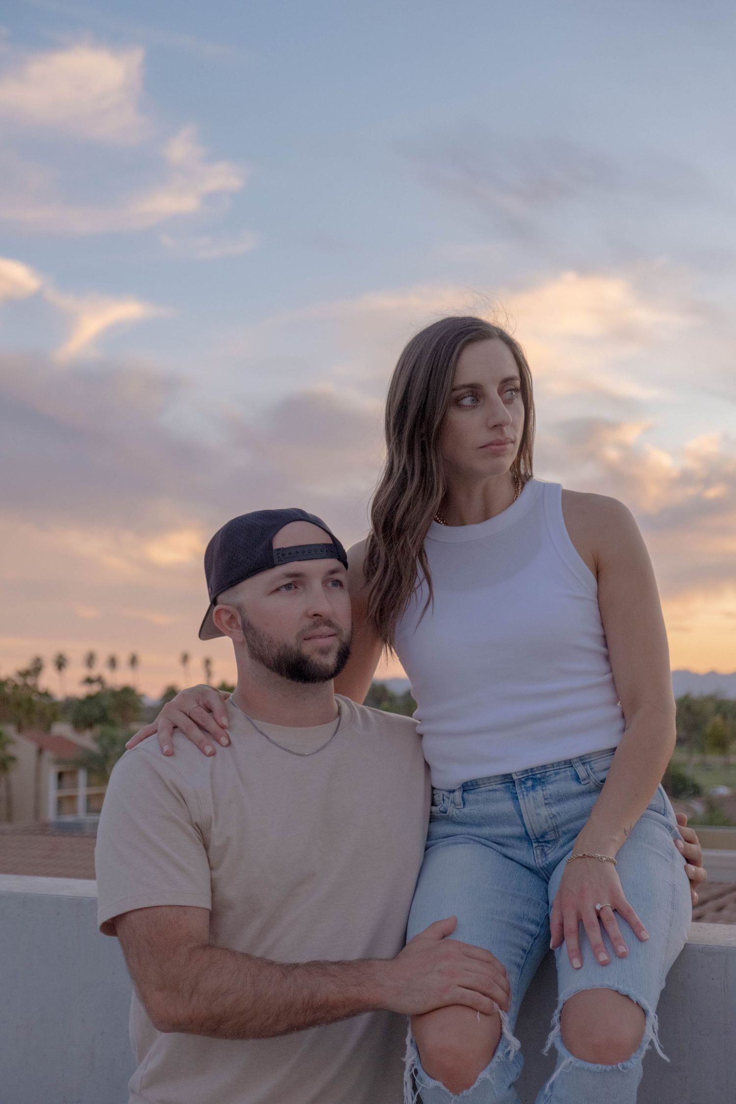 Couple sharing intimate moment at sunset on rooftop with urban backdrop.